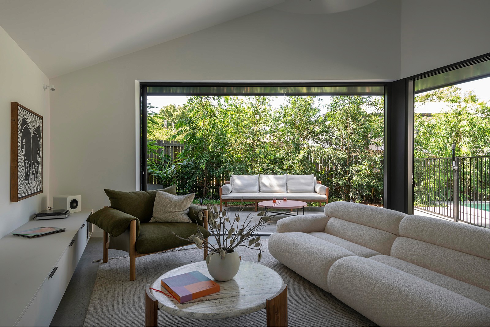 Living room interior at Toohey Forest House with open-plan seating and sliding glass doors opening to landscaped courtyard.