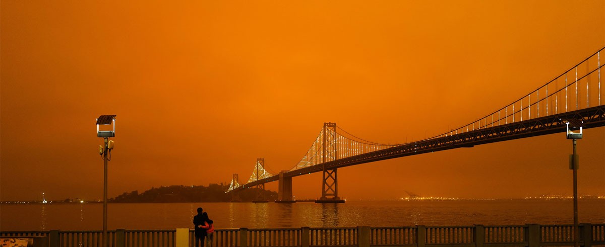 A bridge silhouetted against a striking orange sky, creating a dramatic and atmospheric scene.