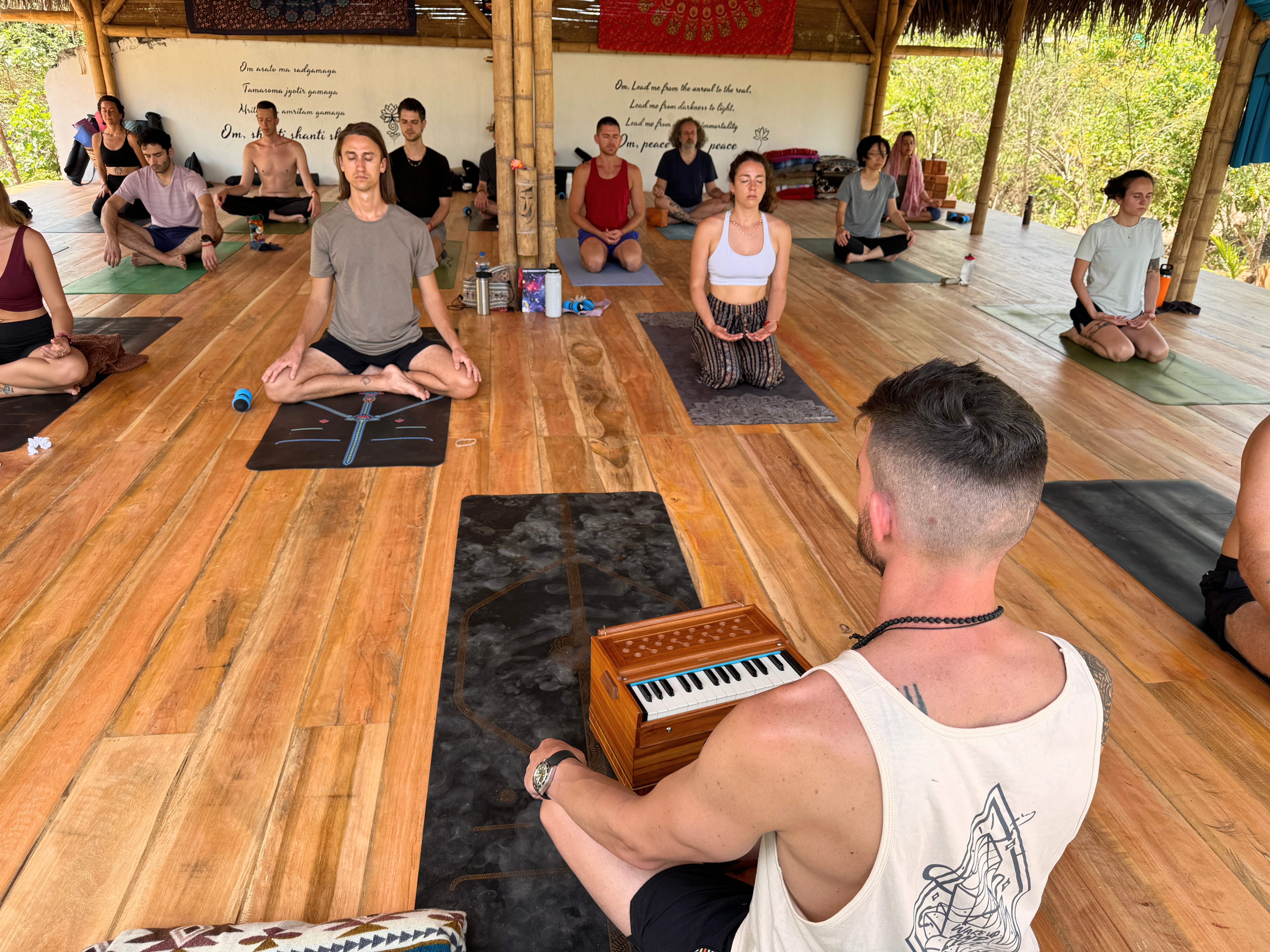 Group yoga retreat participants practicing together in a jungle studio.