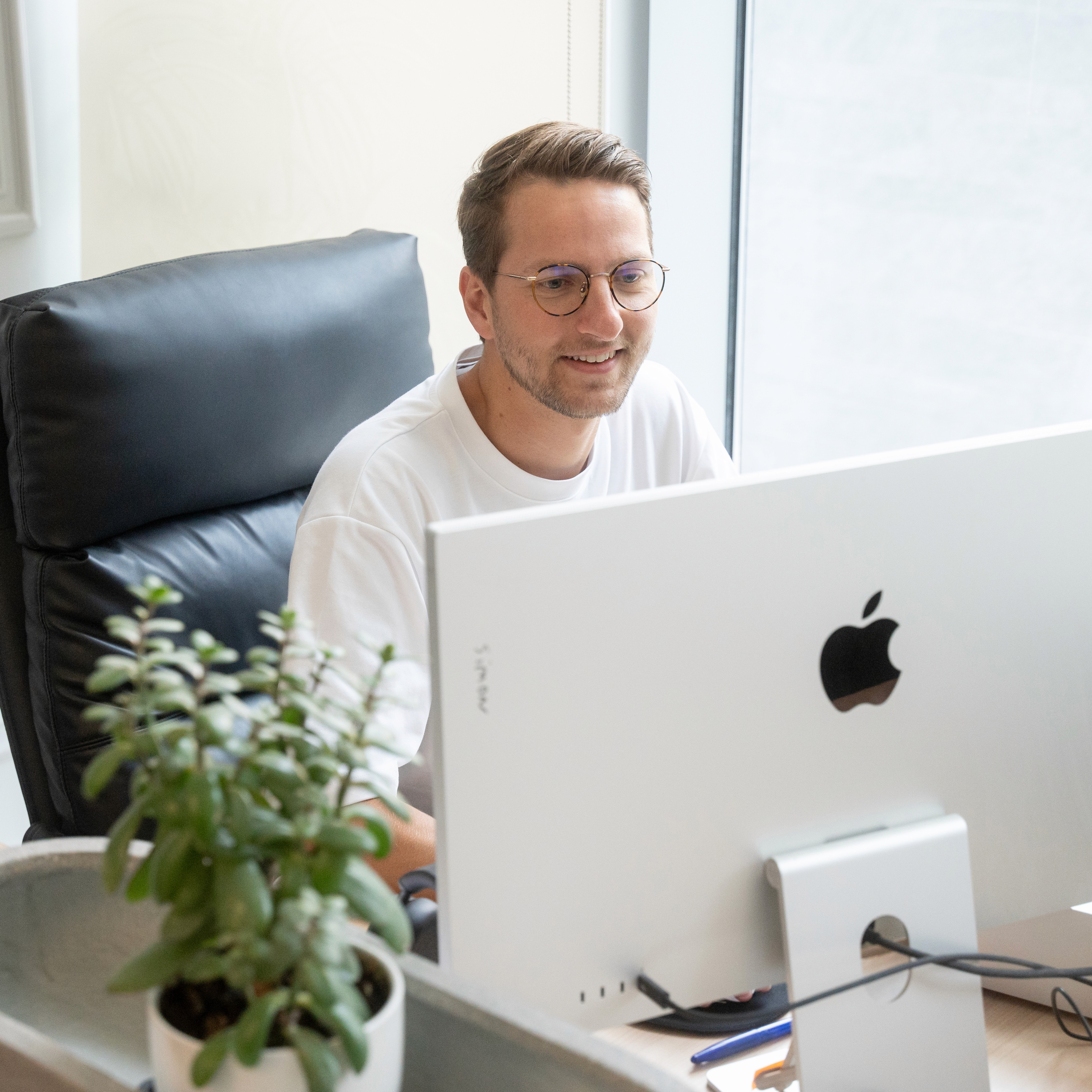 Two people working on laptops in a bright office with large windows