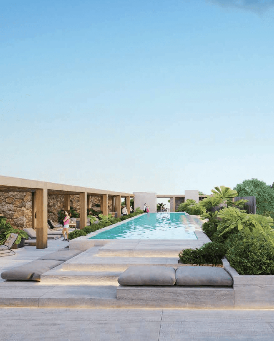 Smiling young woman with long hair standing against a dark green background, holding a finger to her chin.