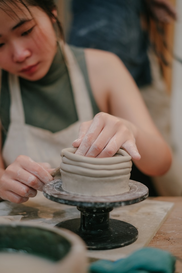 a woman working on a pottery wheel on a table