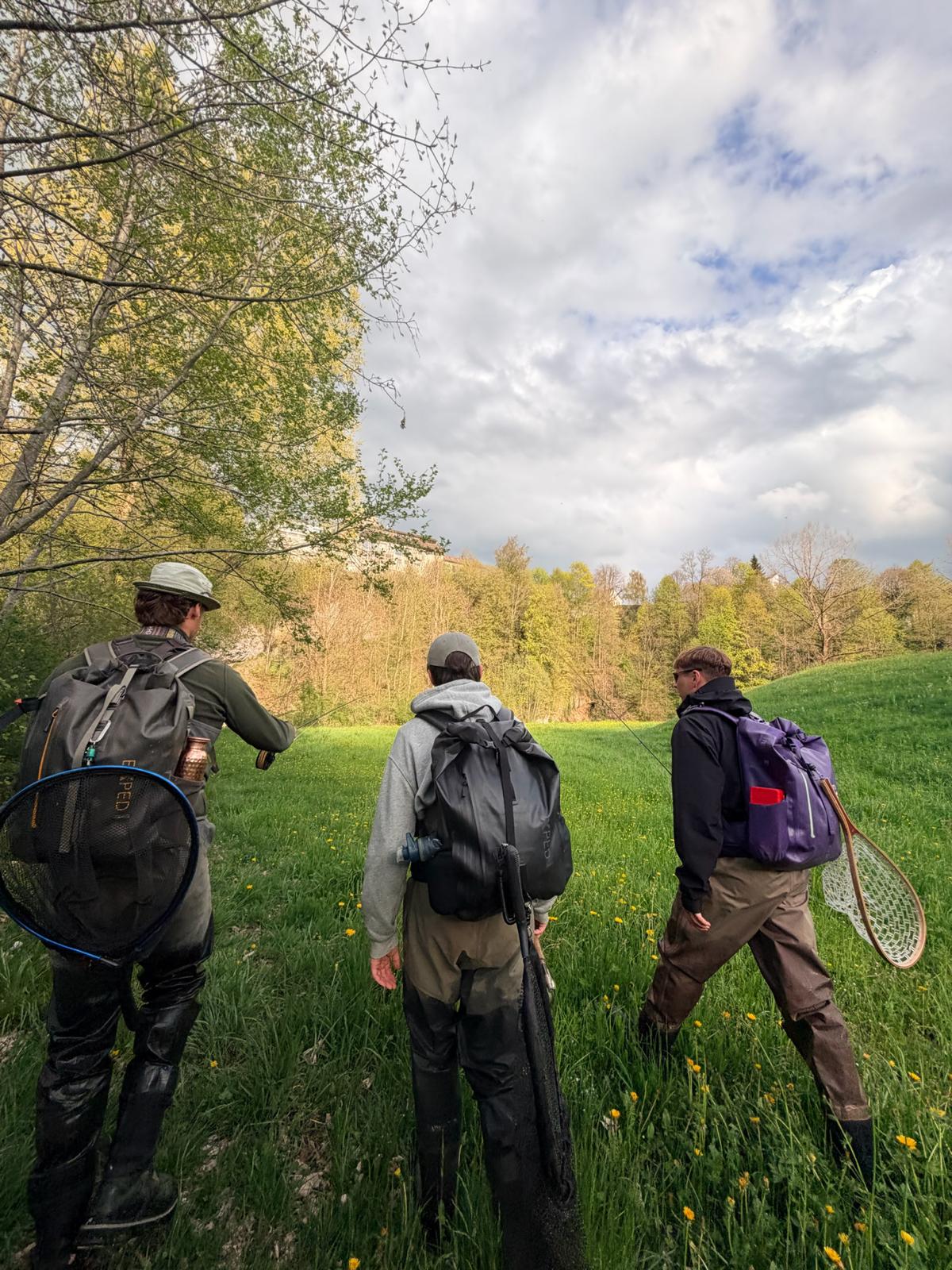 Fabio guiding two fly fishers through a meadow