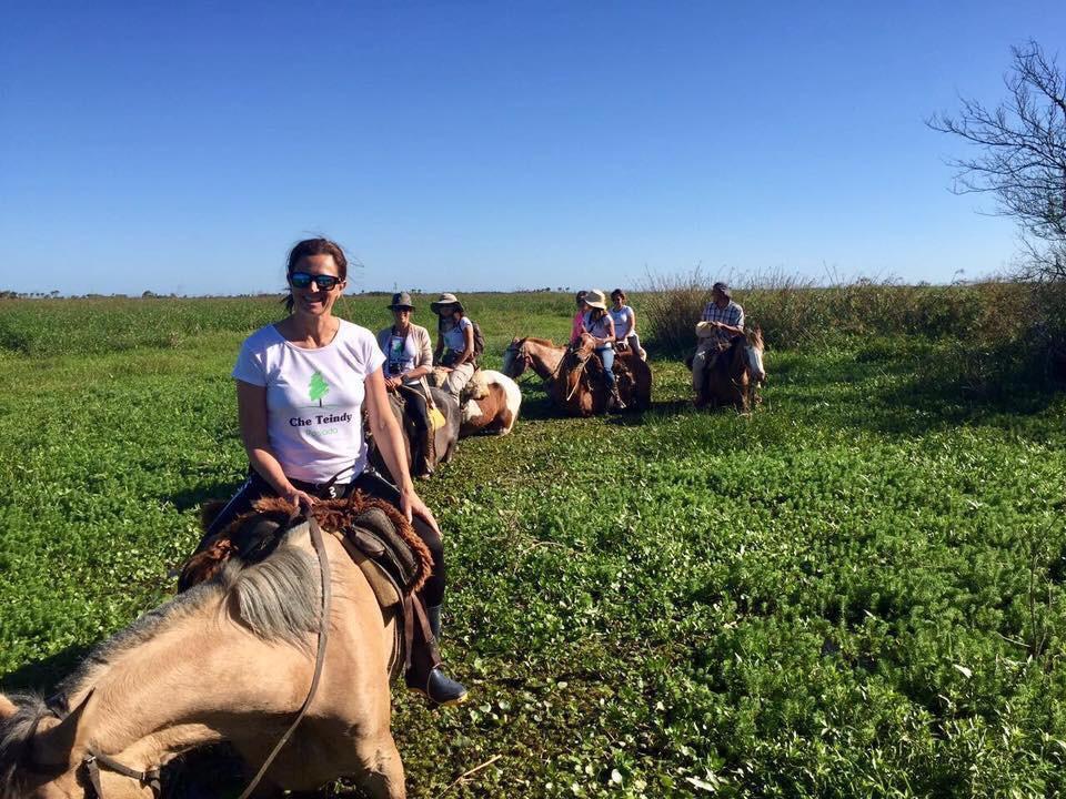 Mujer sentada sobre un tronco frente a una cascada doble en un bosque frondoso de Argentina.