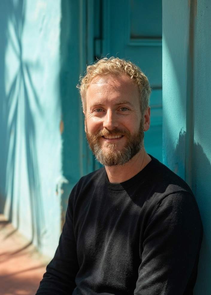 Man sitting against blue wall.