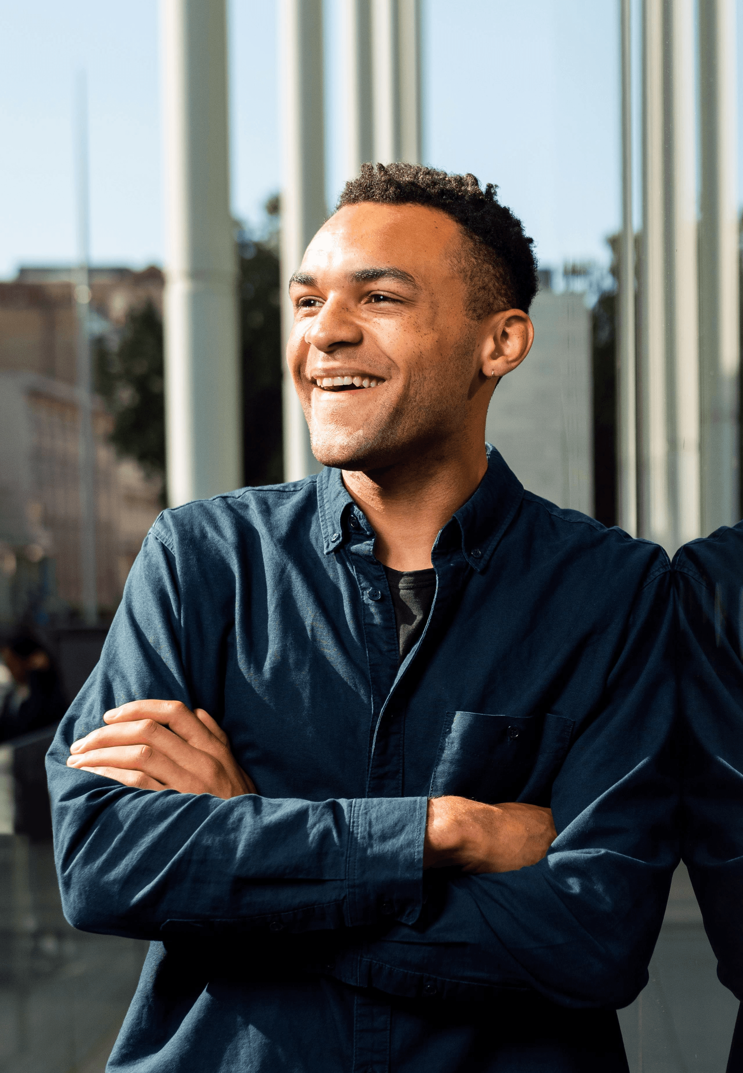 A smiling man leaning against an office building window