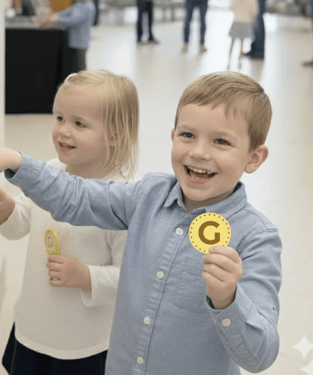 Una persona con una camiseta negra y pantalones de color claro está de pie en la cima rocosa de una montaña al atardecer, sosteniendo una cámara frente a su cara para tomar una foto. Un mar de nubes se extiende detrás de ellos, iluminado por la luz dorada del sol poniente.