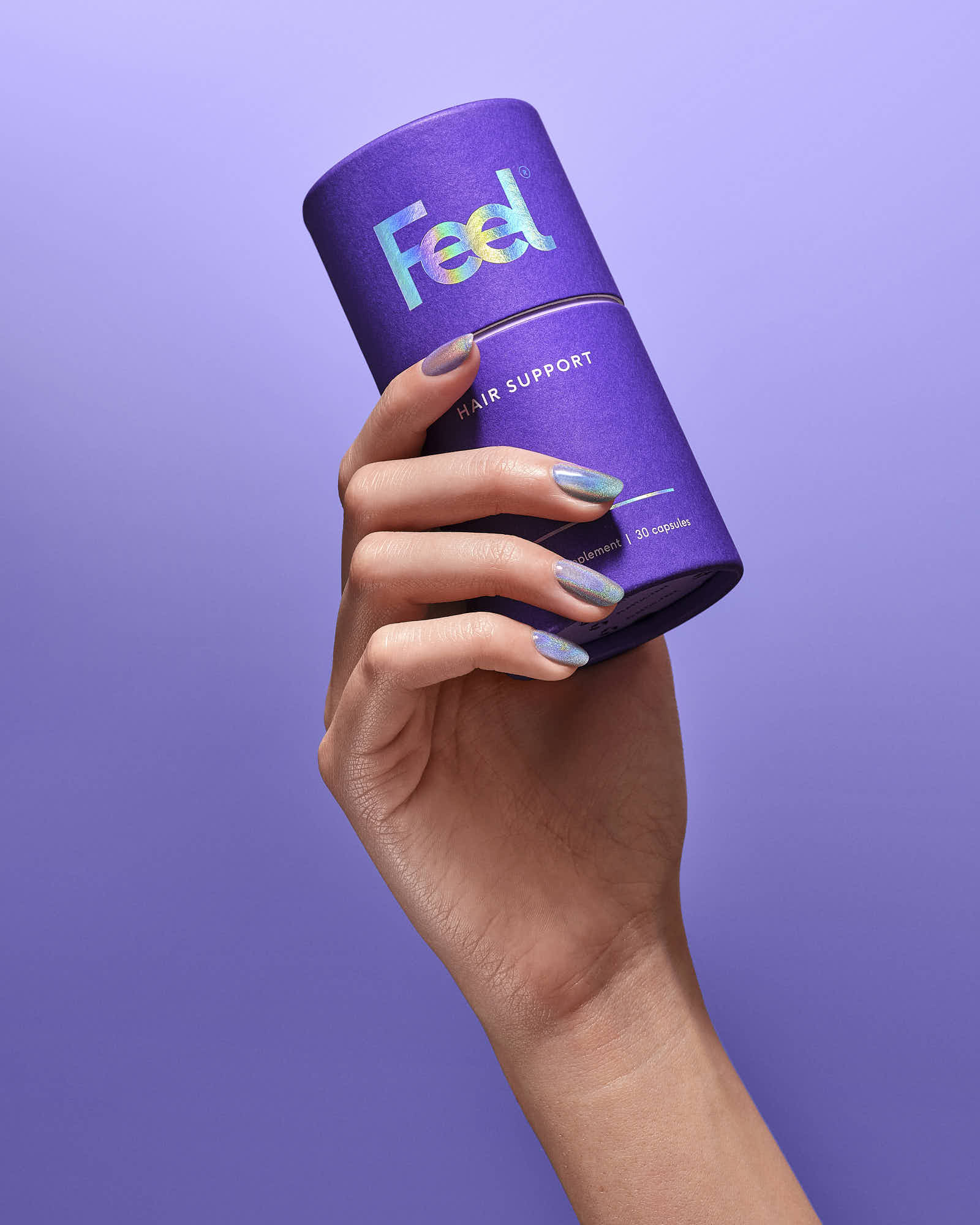 A hand holding a purple cylindrical container against a light purple background.