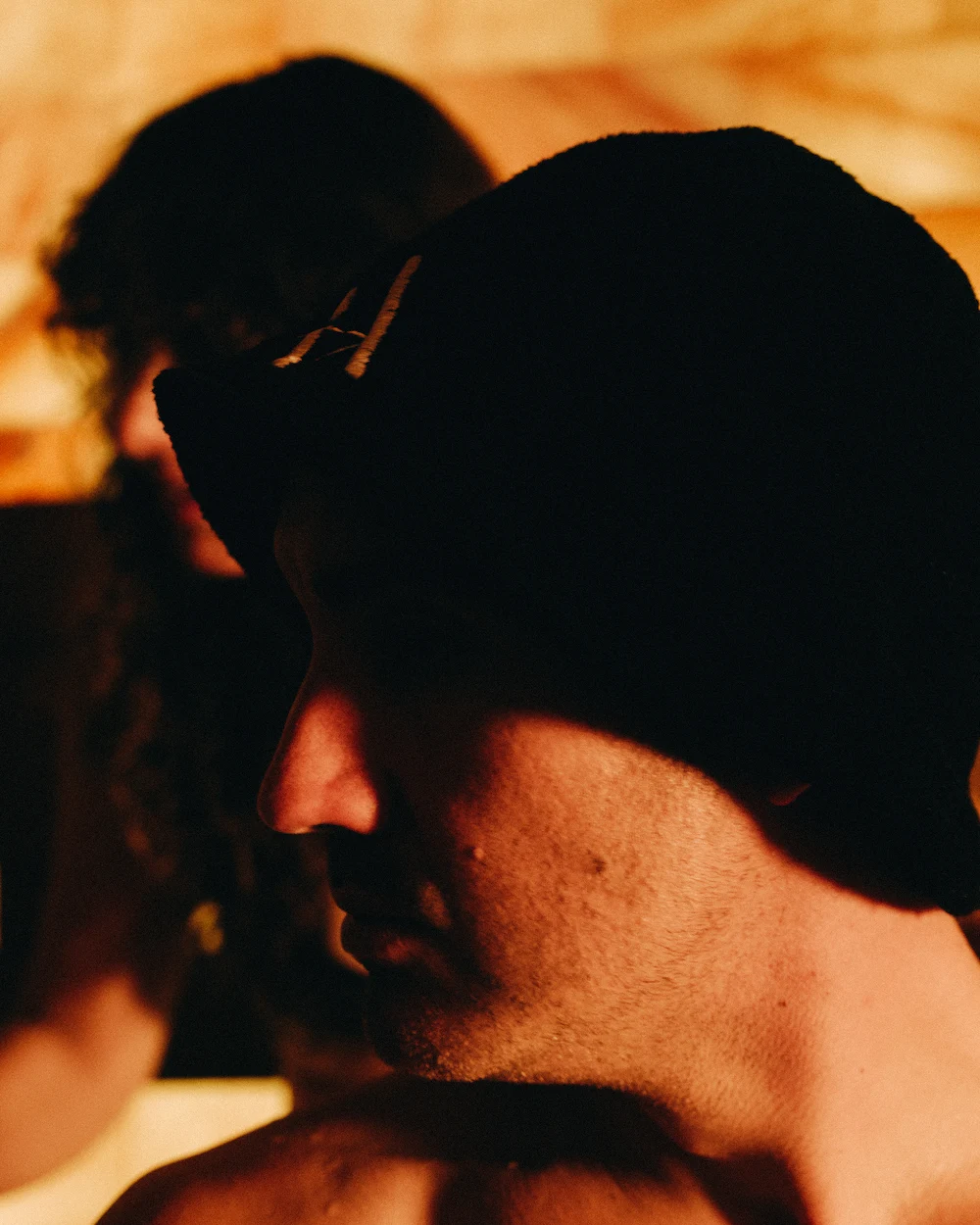Person wearing a traditional felt sauna hat inside a Russian banya, used to protect the head from intense heat during early sauna sessions.