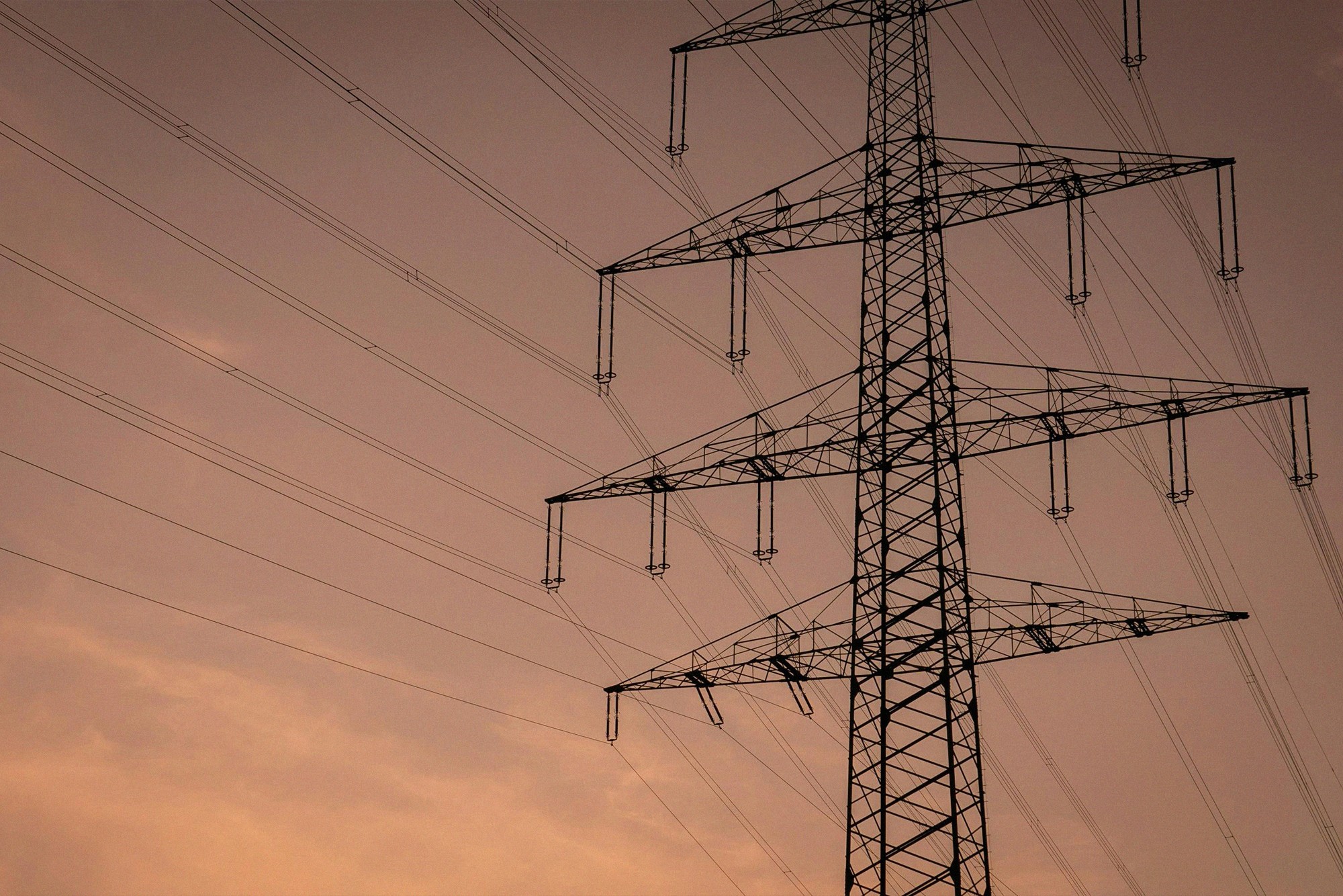 High-voltage power lines at sunset symbolising national energy infrastructure and modern electricity networks.