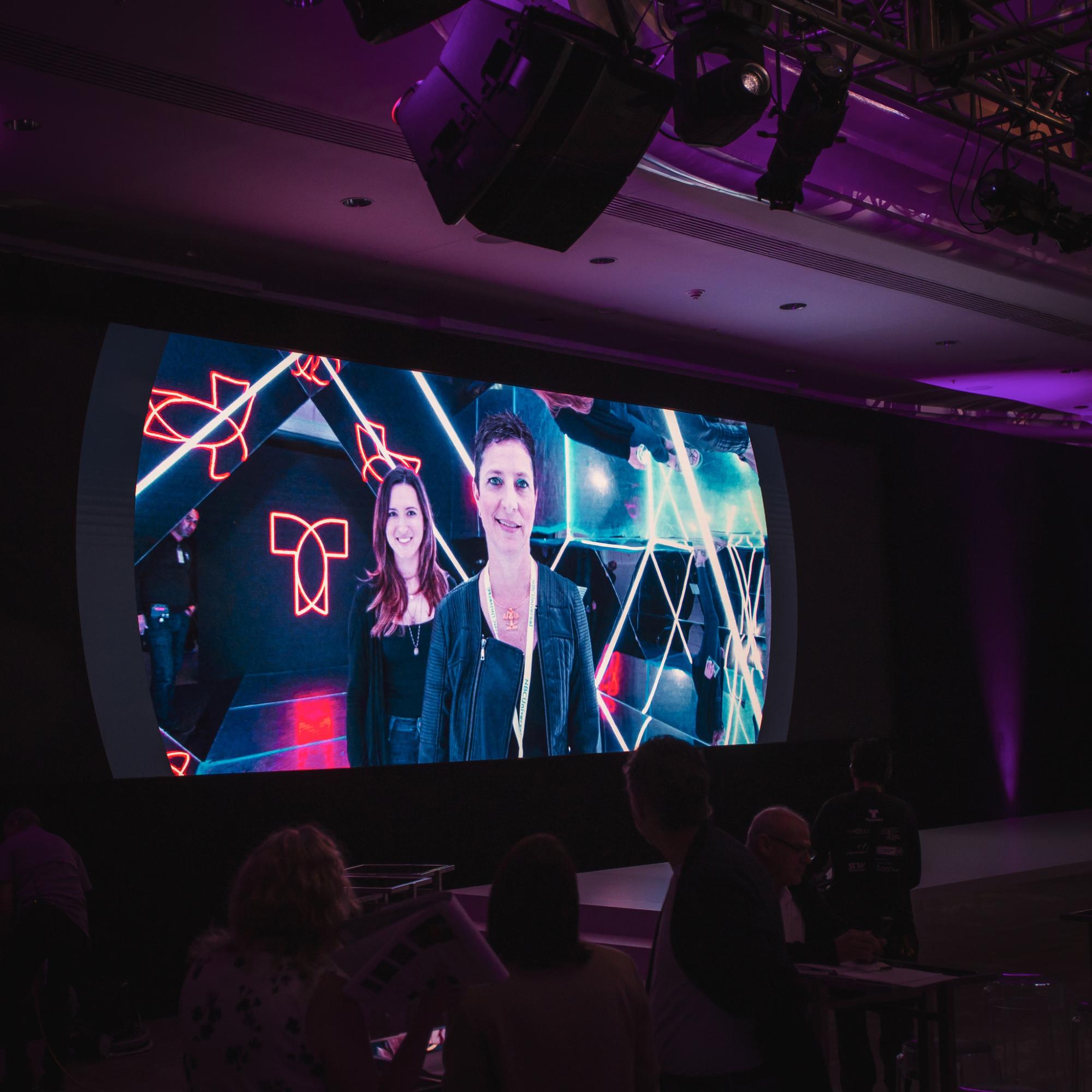 Large event screen displaying branded content playback during a corporate showcase.