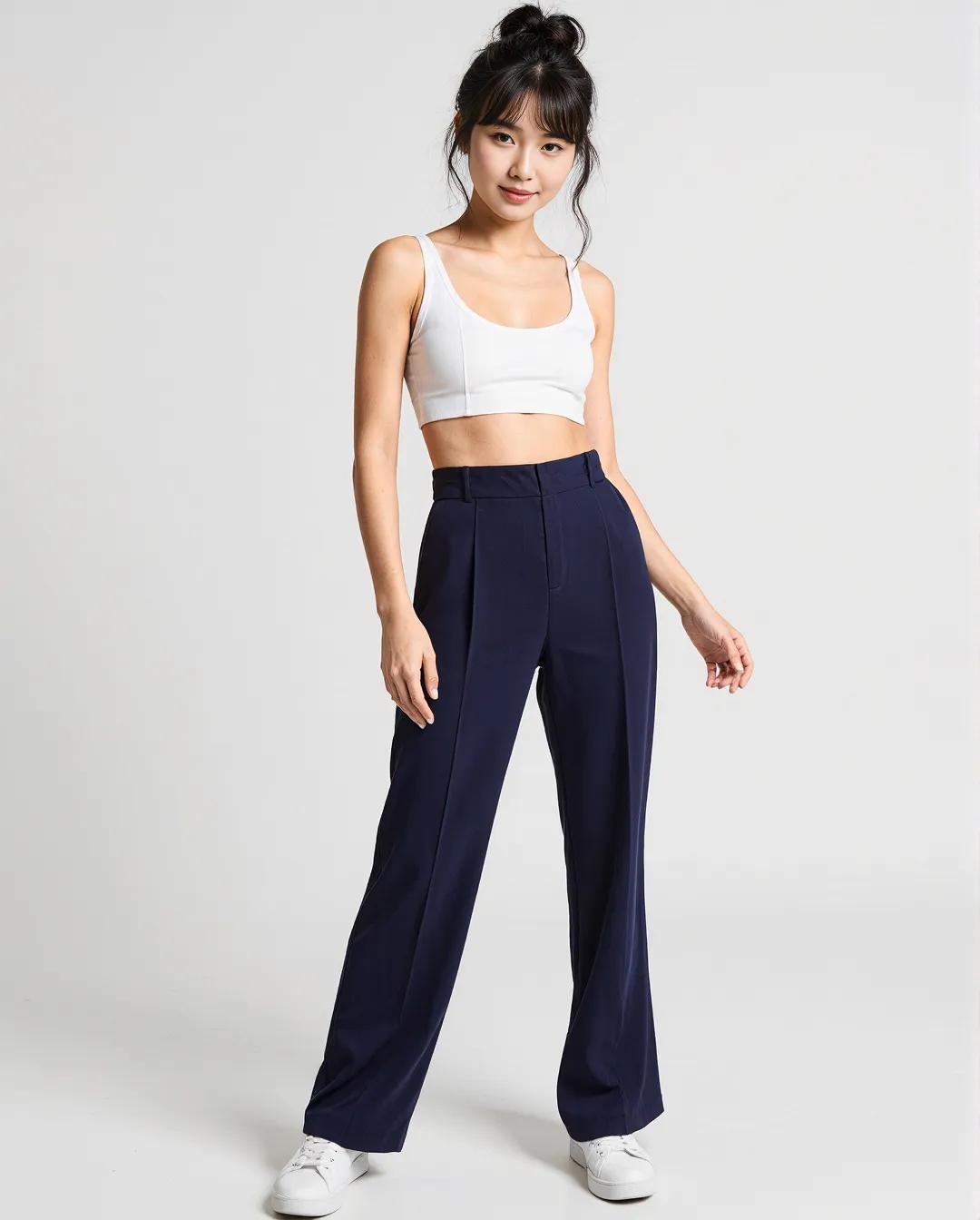 Minimalist fashion photography featuring navy high-waisted trousers and white crop top against clean white background