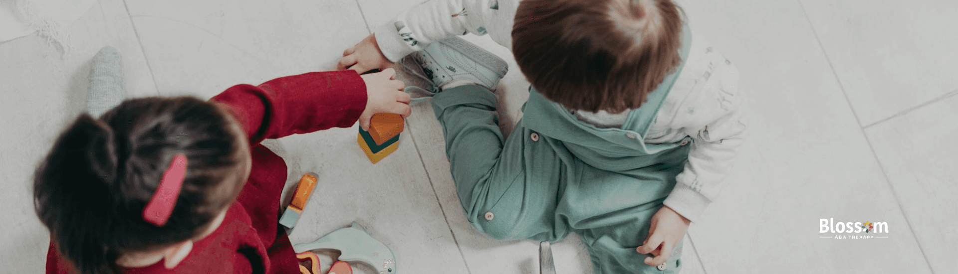 Two autistic toddlers playing with colorful wooden blocks during ABA therapy in Virginia.