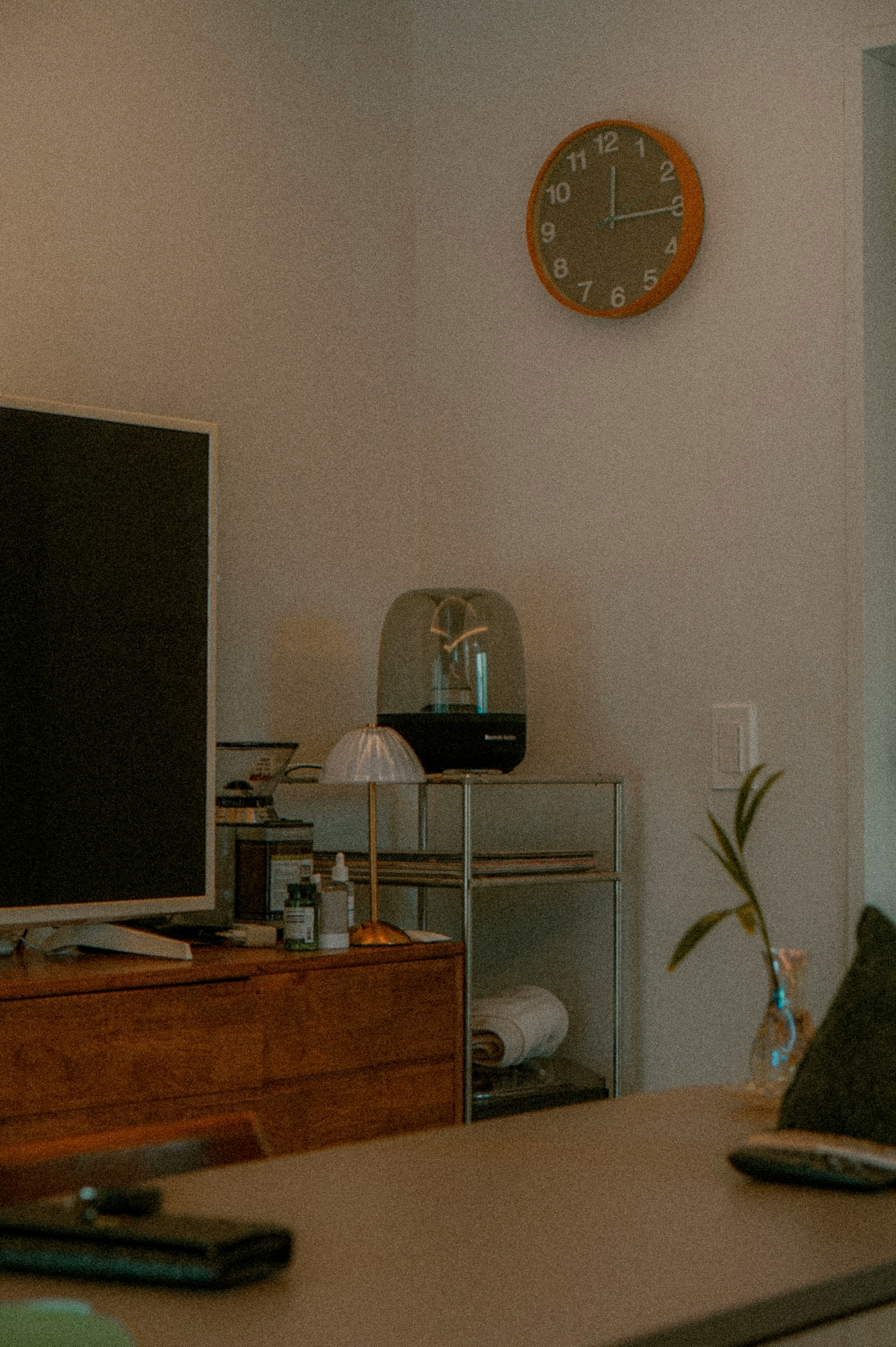 A room with a clock, tv, and decor.