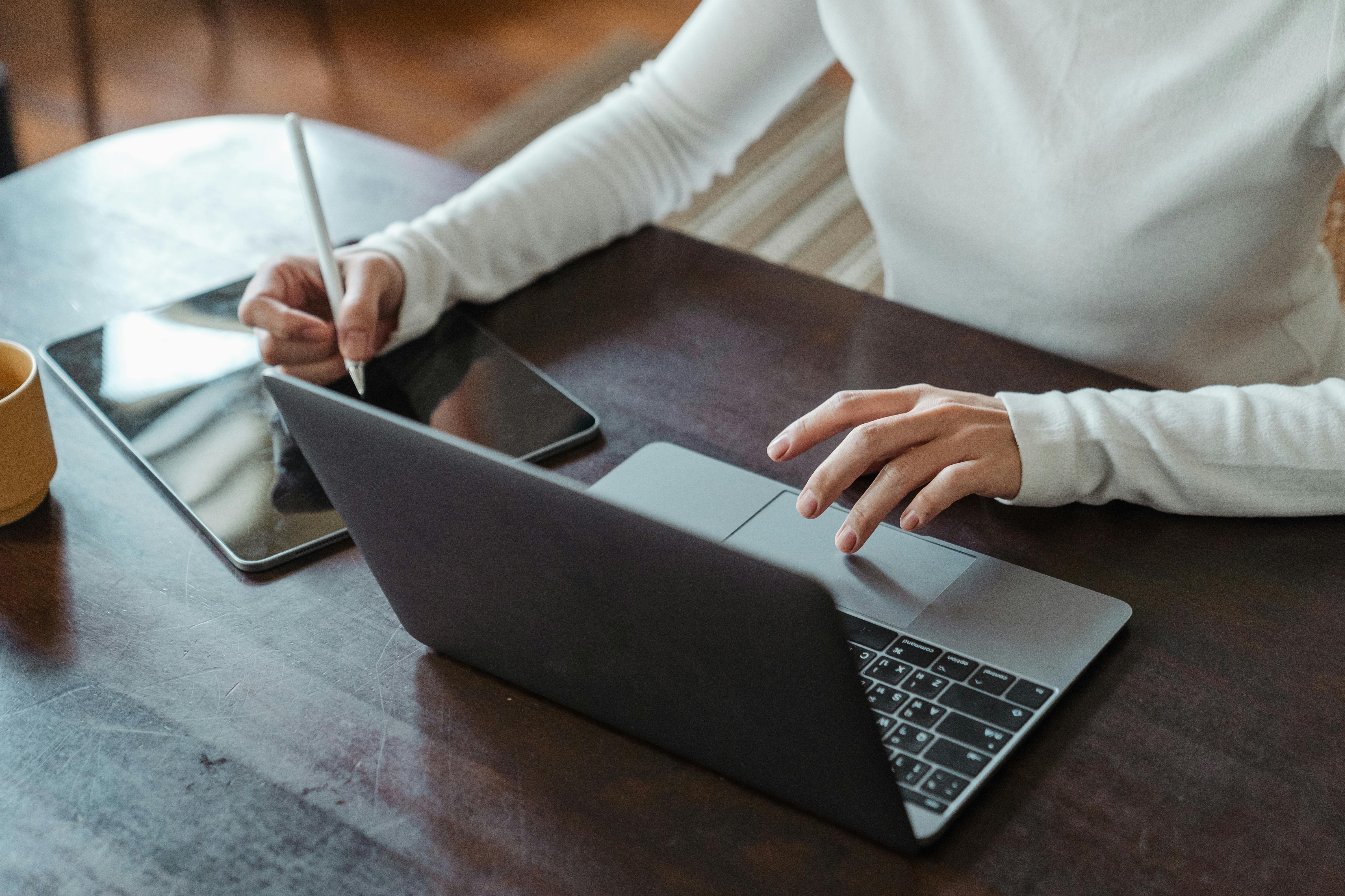 Female Teacher doing multitasking work on a tablet and a laptop