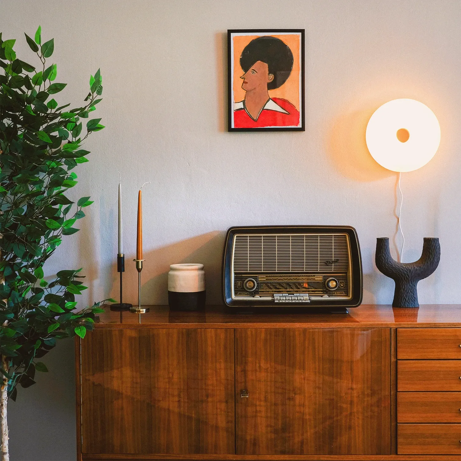 Boutique N°1 • walnut sideboard with a vintage tube radio, candles and a round wall lamp