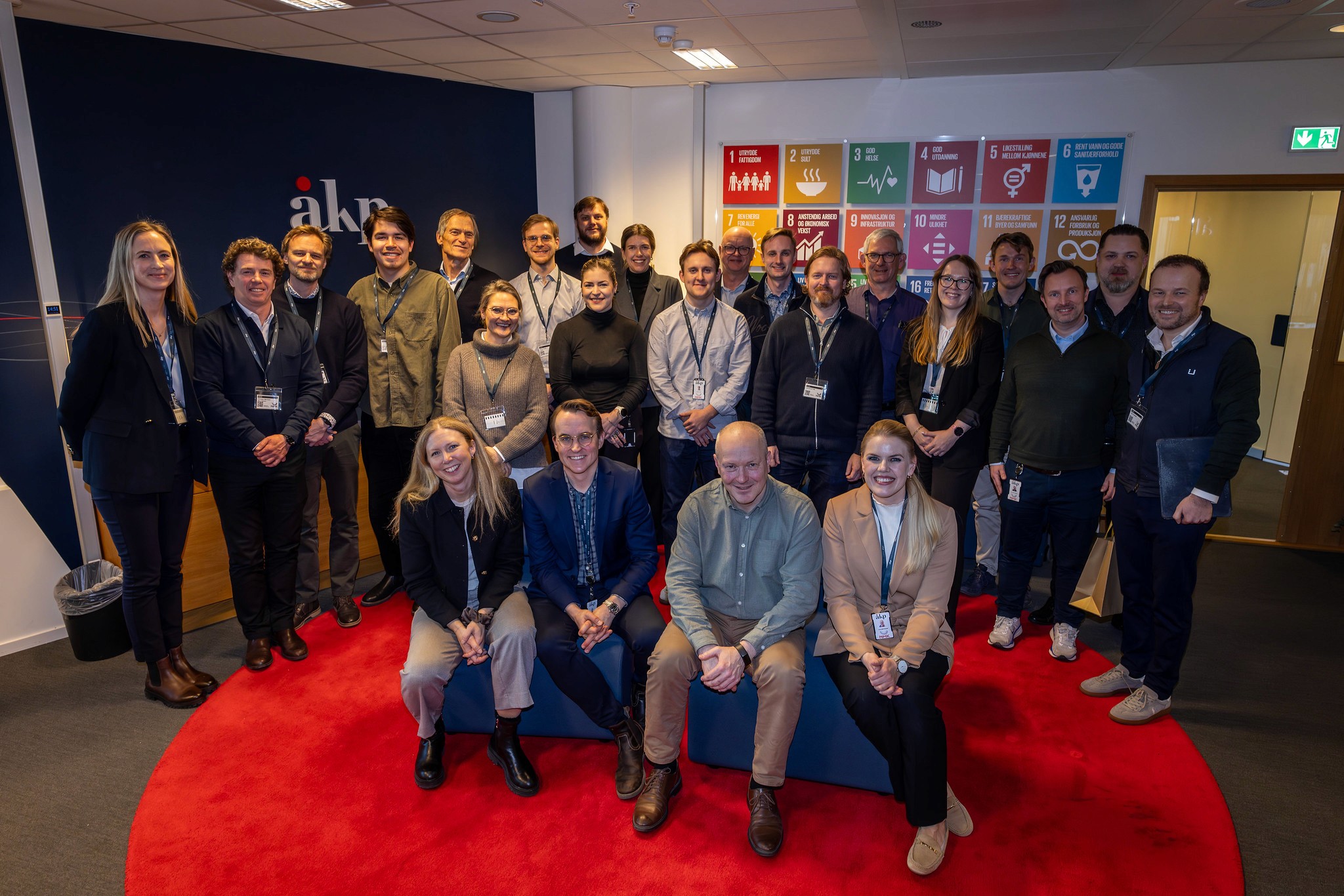 A person wearing a virtual reality headset stands in front of multiple screens, engaged in a digital experience.