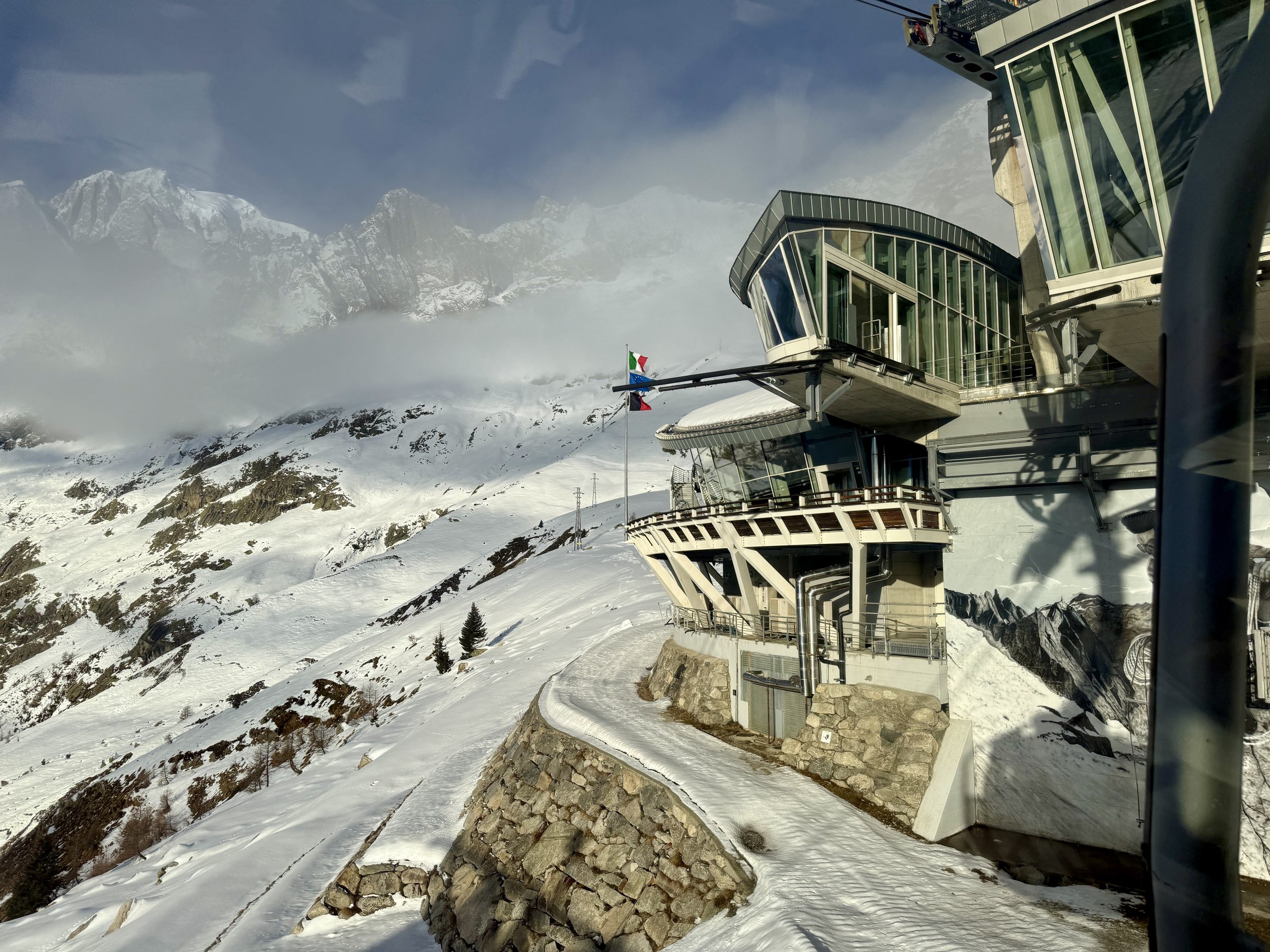 Skyway Monte Bianco Pavillon mid station with flags seen from the cable car above Courmayeur