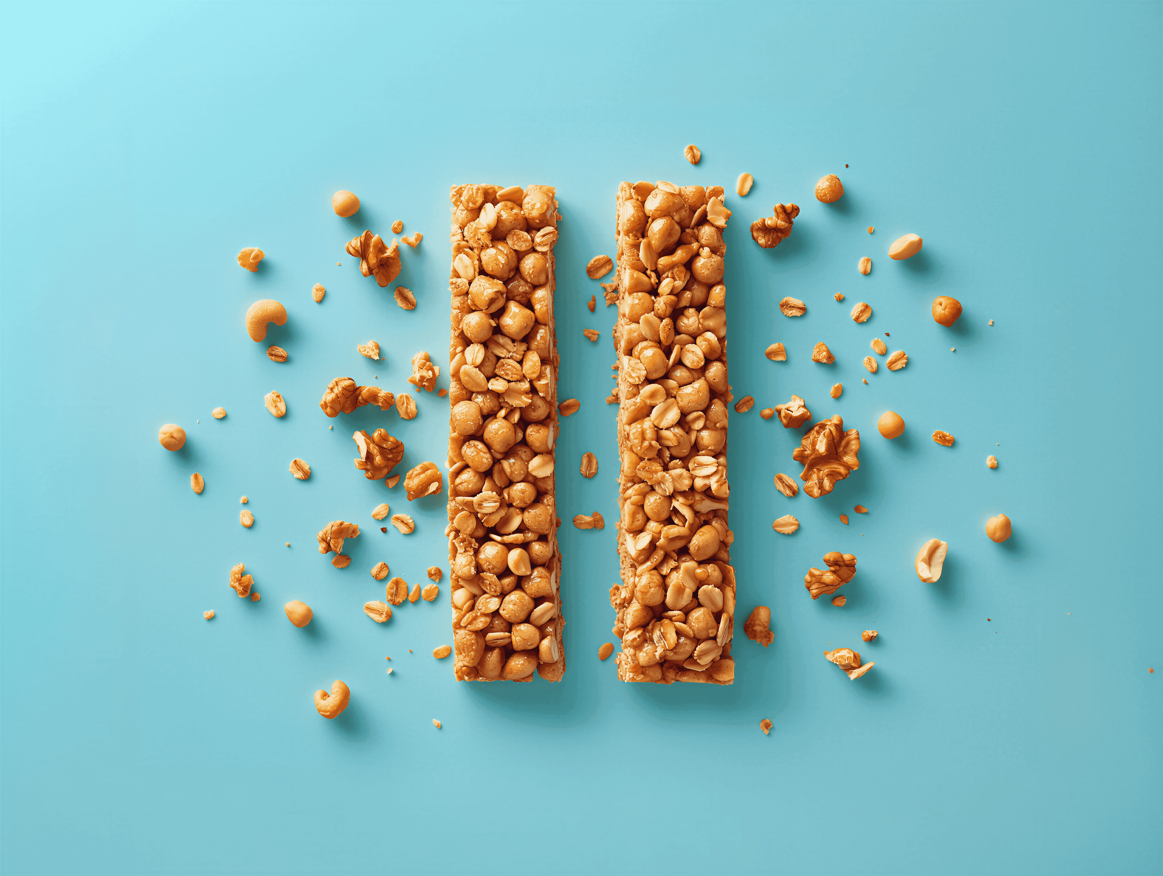 Two granola bars with nuts and oats arranged on a vibrant teal background, with scattered pieces around them.