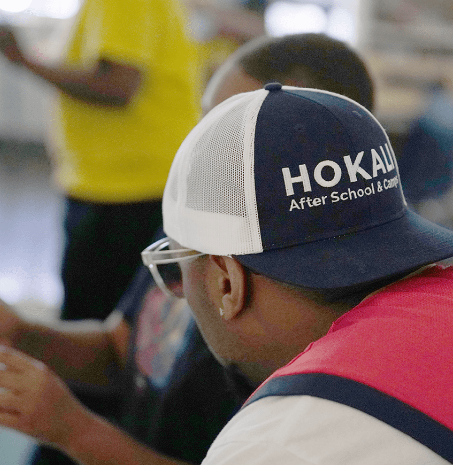 HOKALI educator helping a child during aftercare, highlighting attentive supervision and student-centered support.