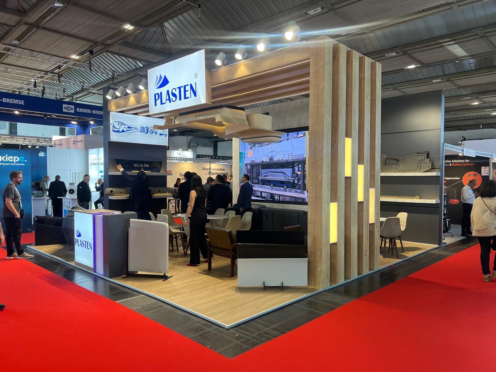 Suspended automobile ceiling component displayed in the middle of the Plasten stand, showcasing real automotive plastic parts.