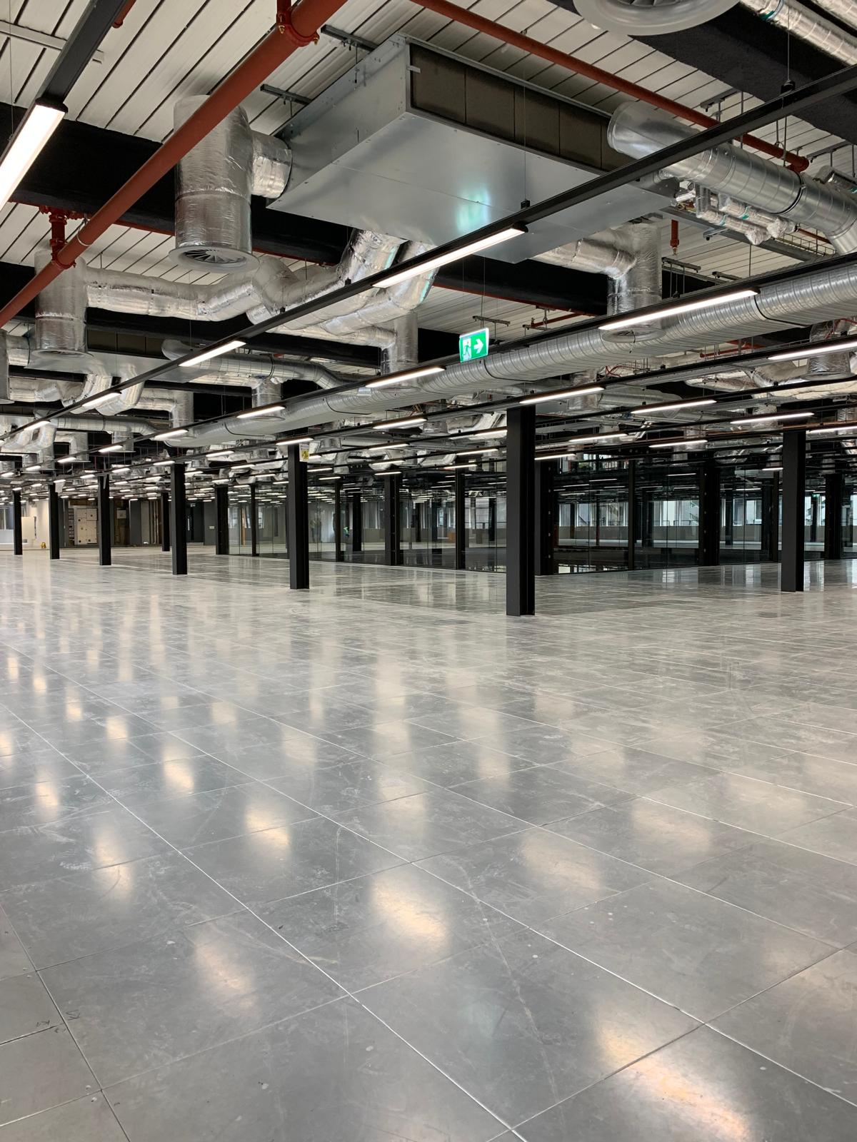 An elegant modern home with balconies, well-lit interiors and surrounded by greenery at dusk.