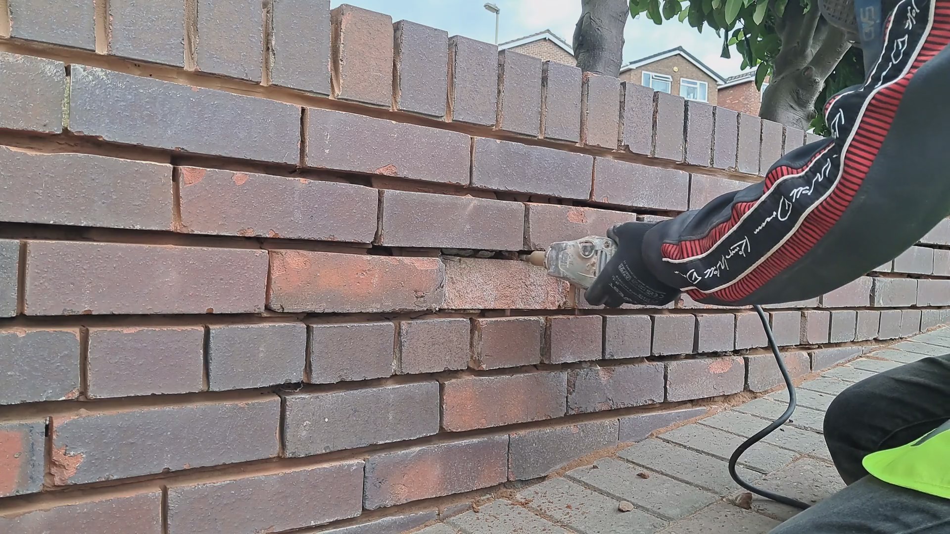 A man removing a damaged brick from a garden wall