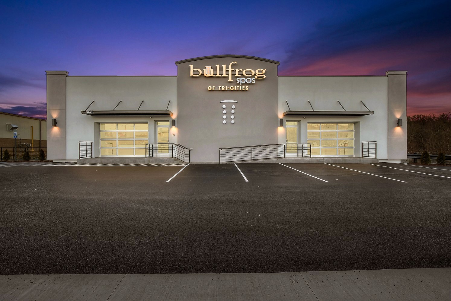 Exterior of a modern building at dusk, featuring large windows and a clear sky with purple hues.
