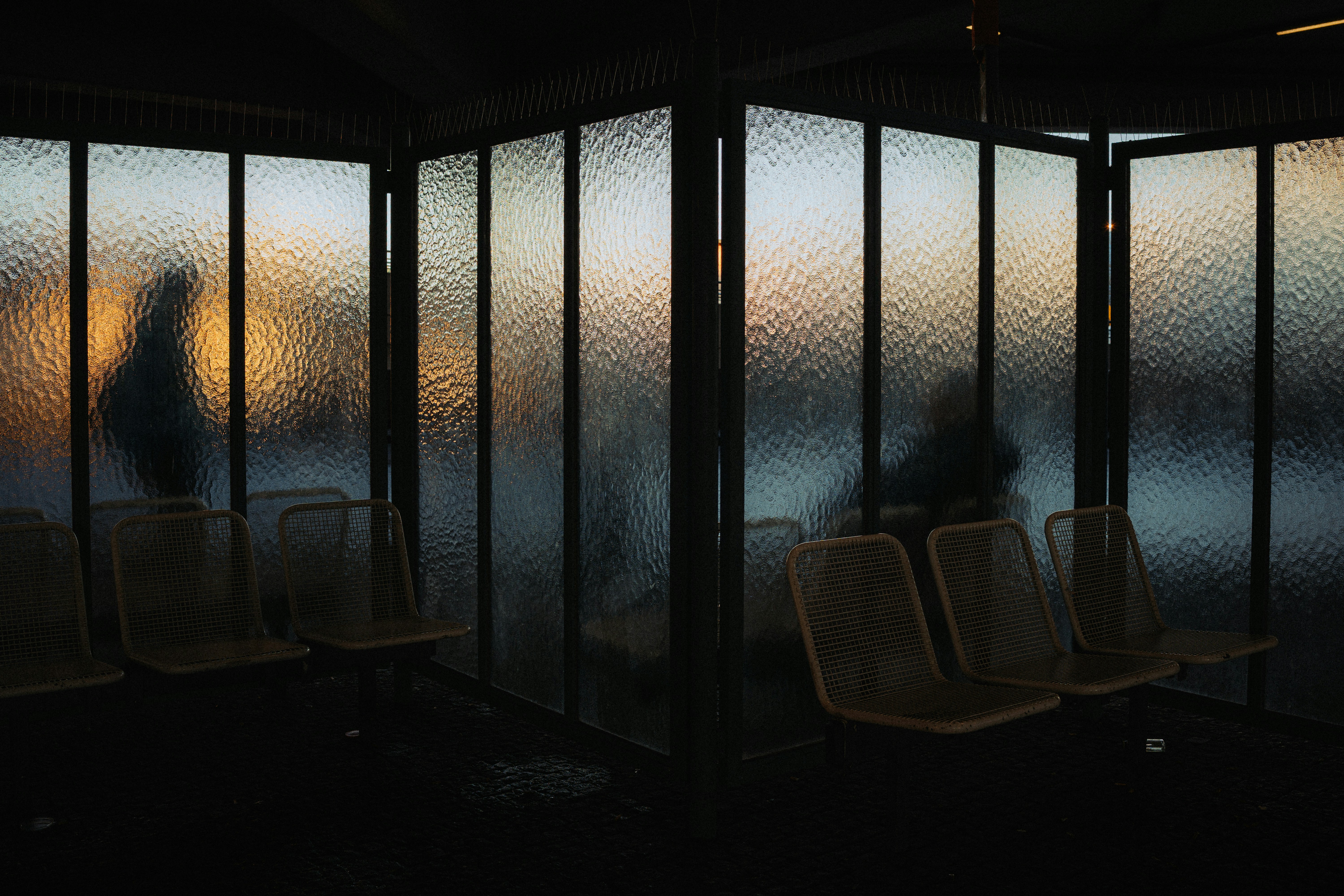 Silhouettes of people in a waiting area at sunset