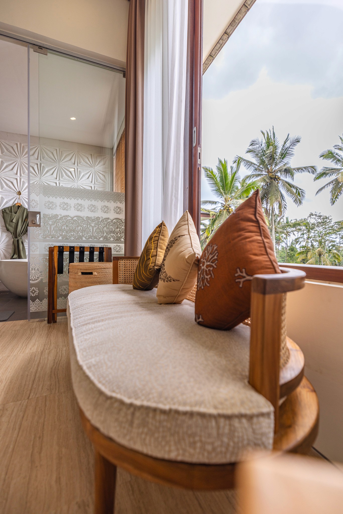 Detailaufnahme eines stilvollen Hotelzimmers – Dekor mit handgefertigten Kissen in den Khastana Hadi Luxury Villas, Bali im Hintergrund Palmen