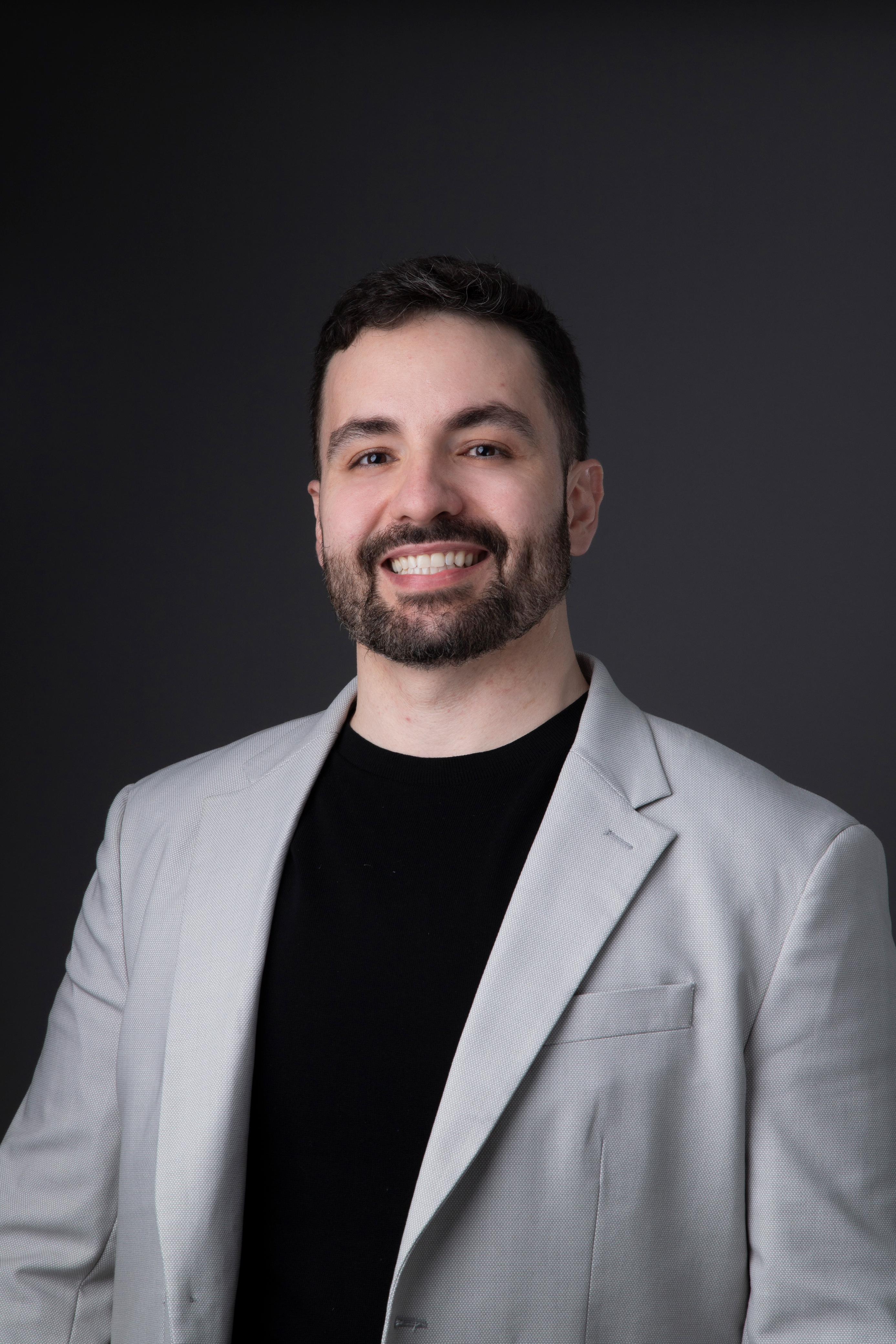 Image of doctor Vinícius Salgado sitting at his office desk looking and smiling at the camera.