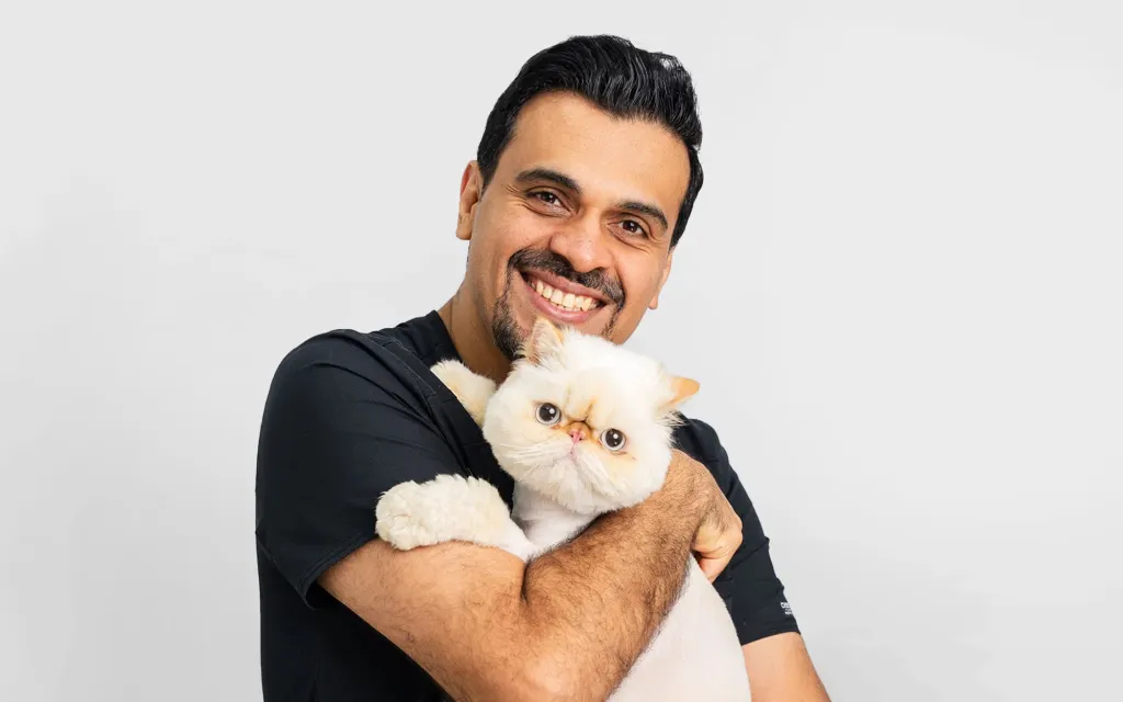 Dr. Soheyl Simaei smiling while holding a fluffy white cat.