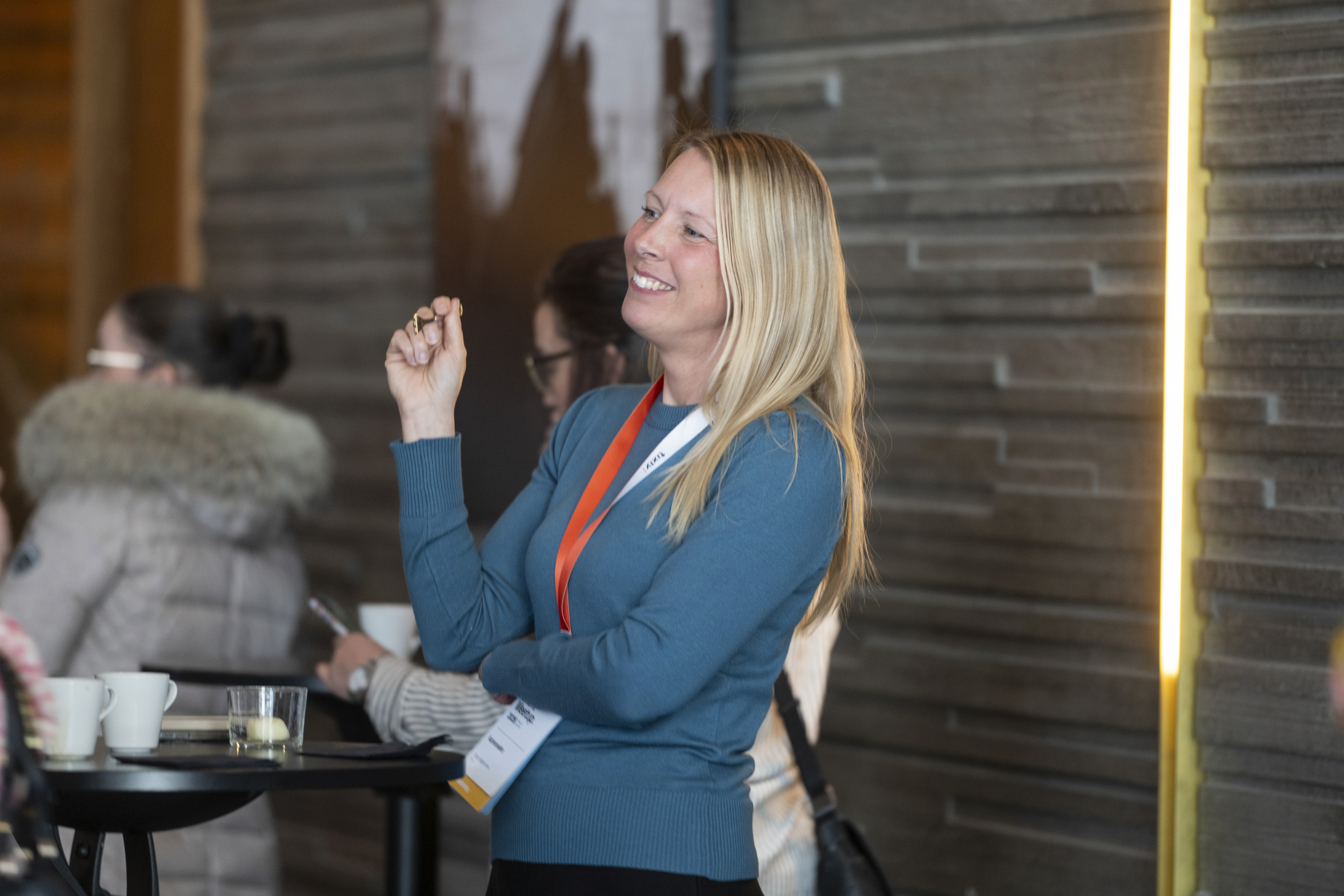 A blonde woman smiles while holding a drink