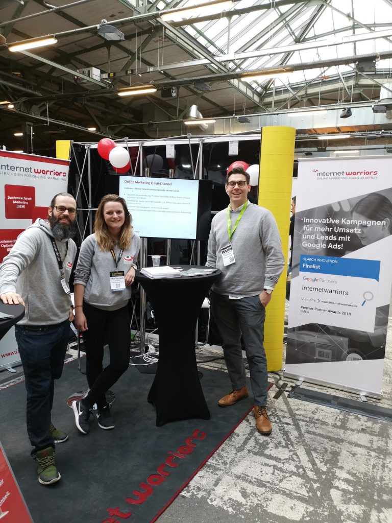 internetwarriors Team auf dem Messestand der Expo Berlni 2019 in grauen Hoodies