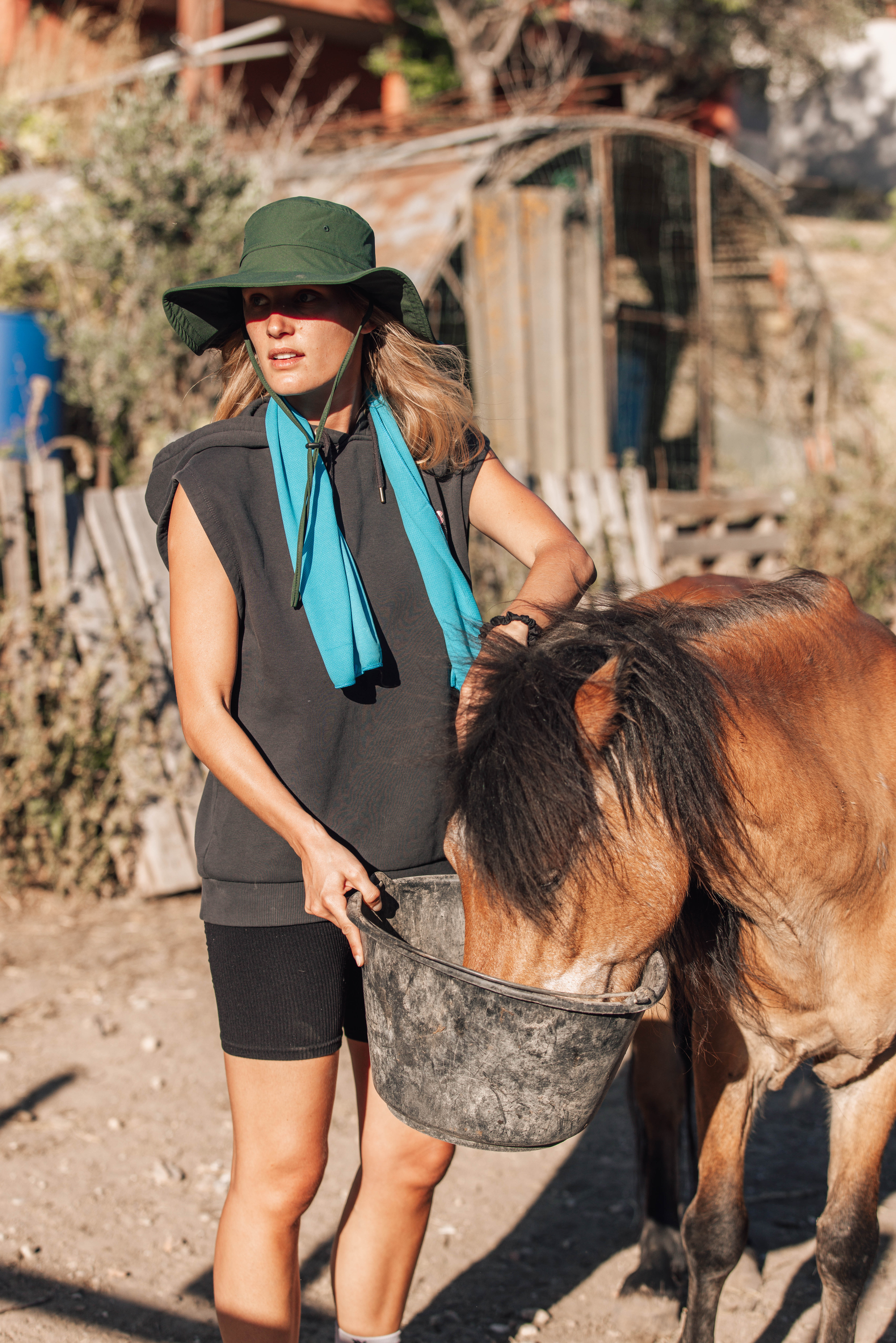 Woman wearing the khaki G-Heat cooling UV-protection hat during an outdoor horseback riding activity