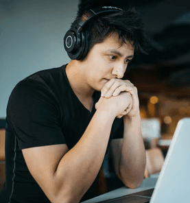 man wearing headphones while sitting on chair in front of MacBook