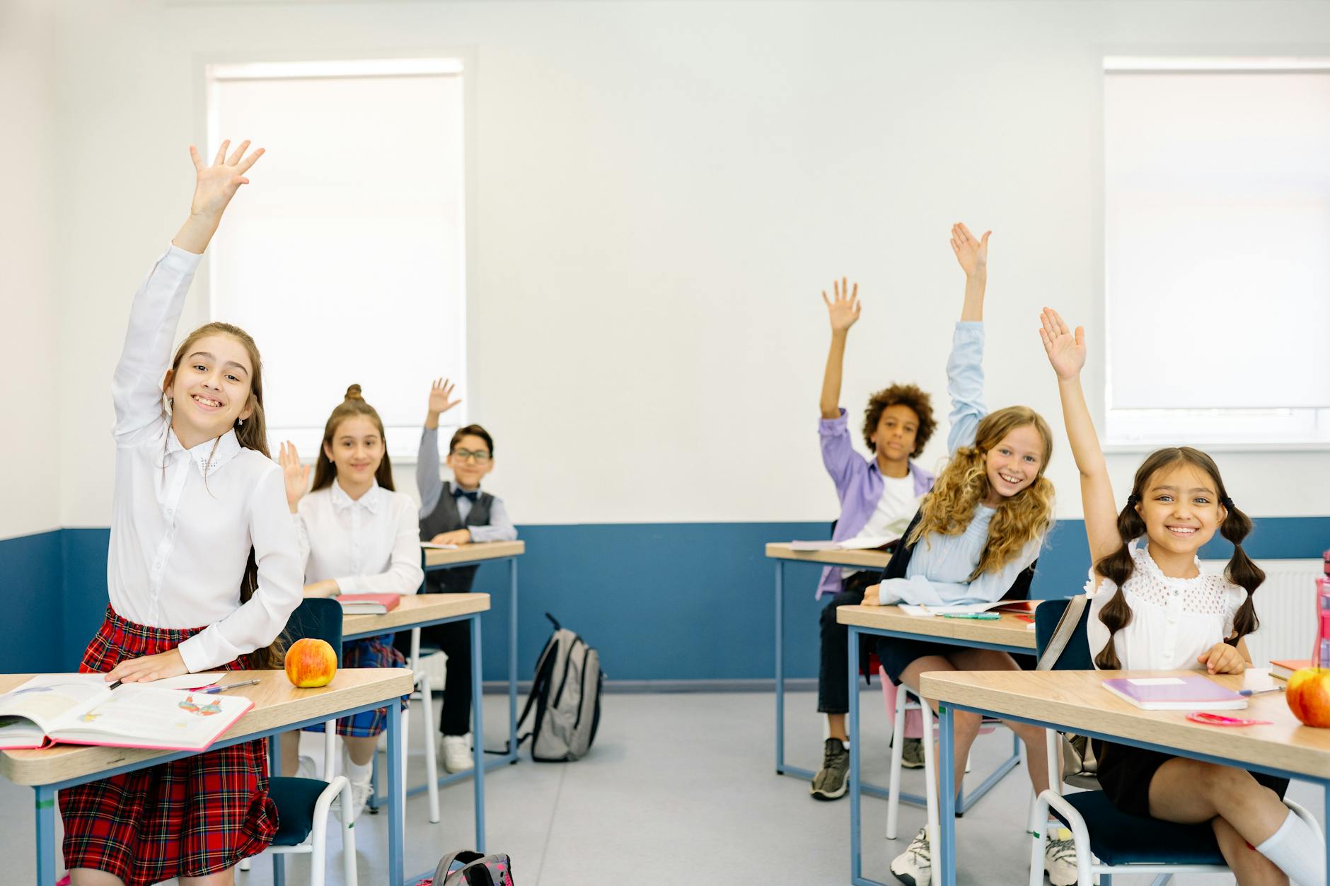 A smiling elementary student raising her hand confidently during a fast-paced direct instruction lesson.