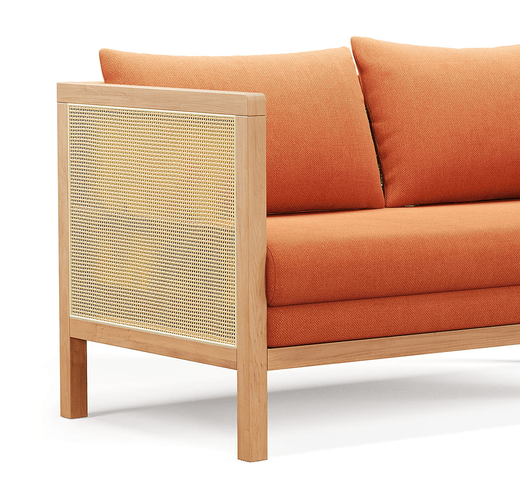 Wooden sofa with woven cane side panel and orange cushions, close-up detail render