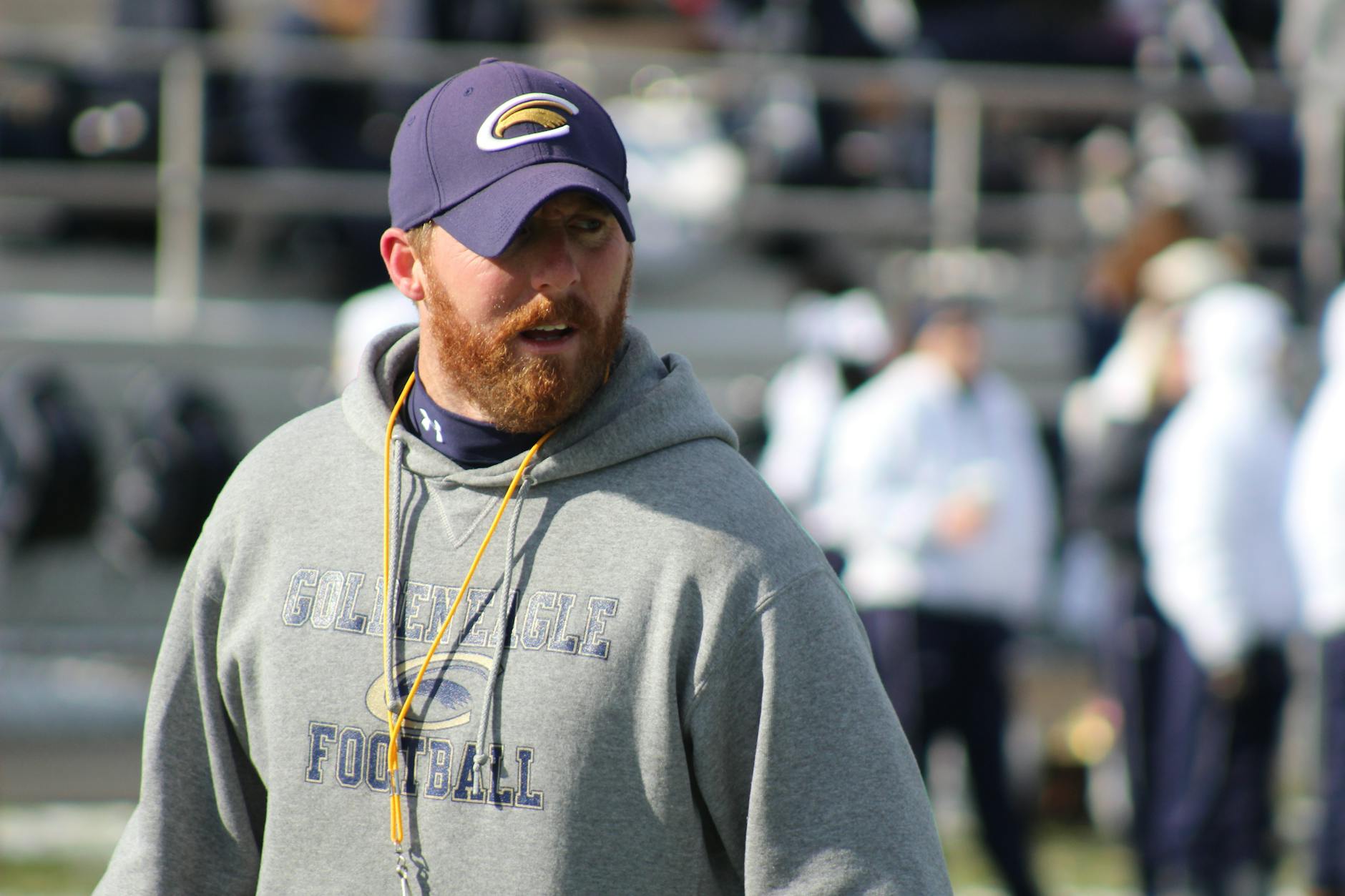 College football coach reviewing plays with clipboard on sideline