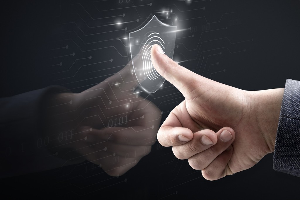 Dedo tocando escudo digital holográfico com ícone de impressão digital, representando autenticação biométrica e segurança da informação em TI - FindUP - Segurança cibernética