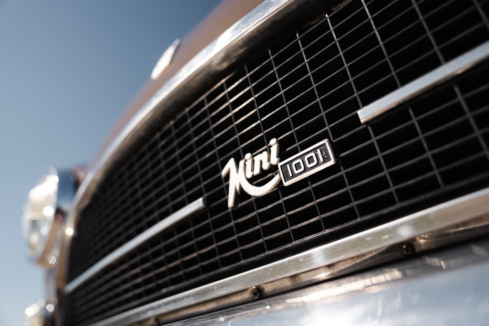 Close-up of a vehicle's front grille, showcasing the logo and chrome accents against a clear blue sky.