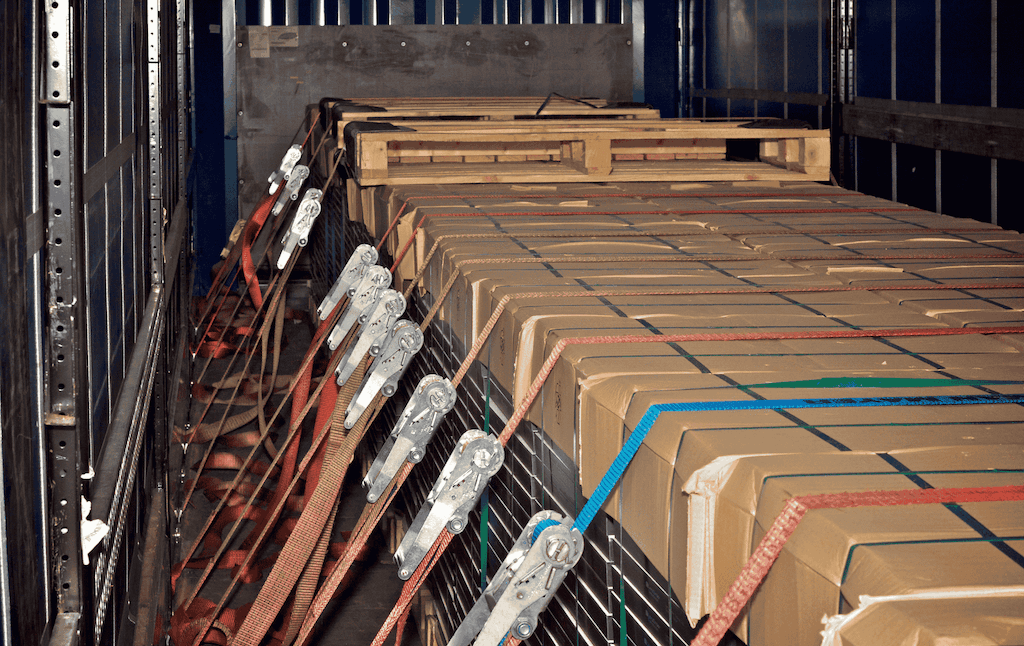 argo truck transporting a shipping container on a highway during sunset.