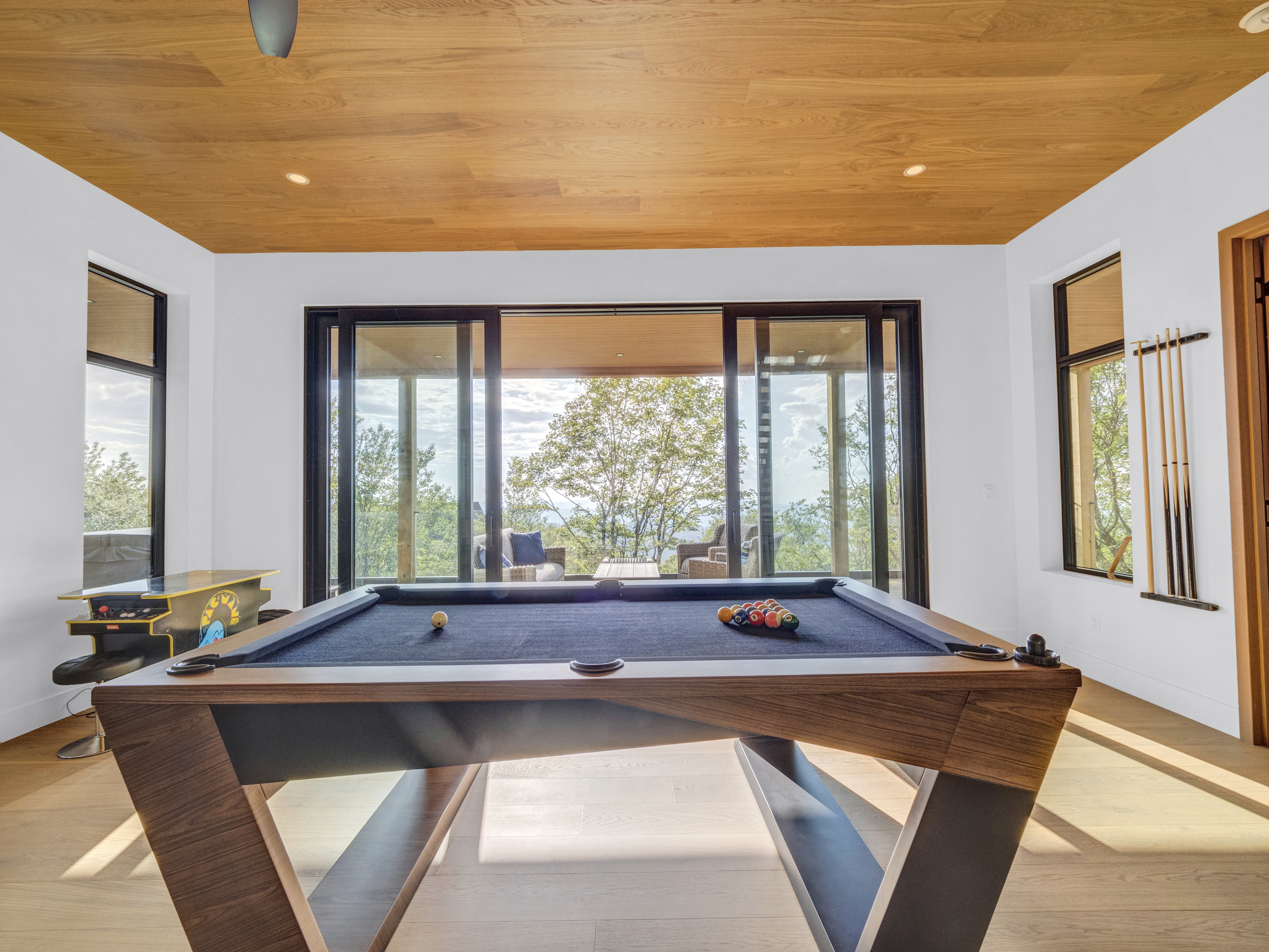 Elevated view of the illuminated rear decks, featuring an outdoor sectional, fire pit, dining area, and hot tub at dusk