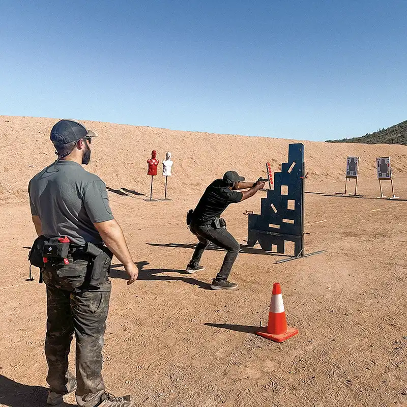 Tactical firearms training course with instructor and student practicing shooting drills at outdoor range