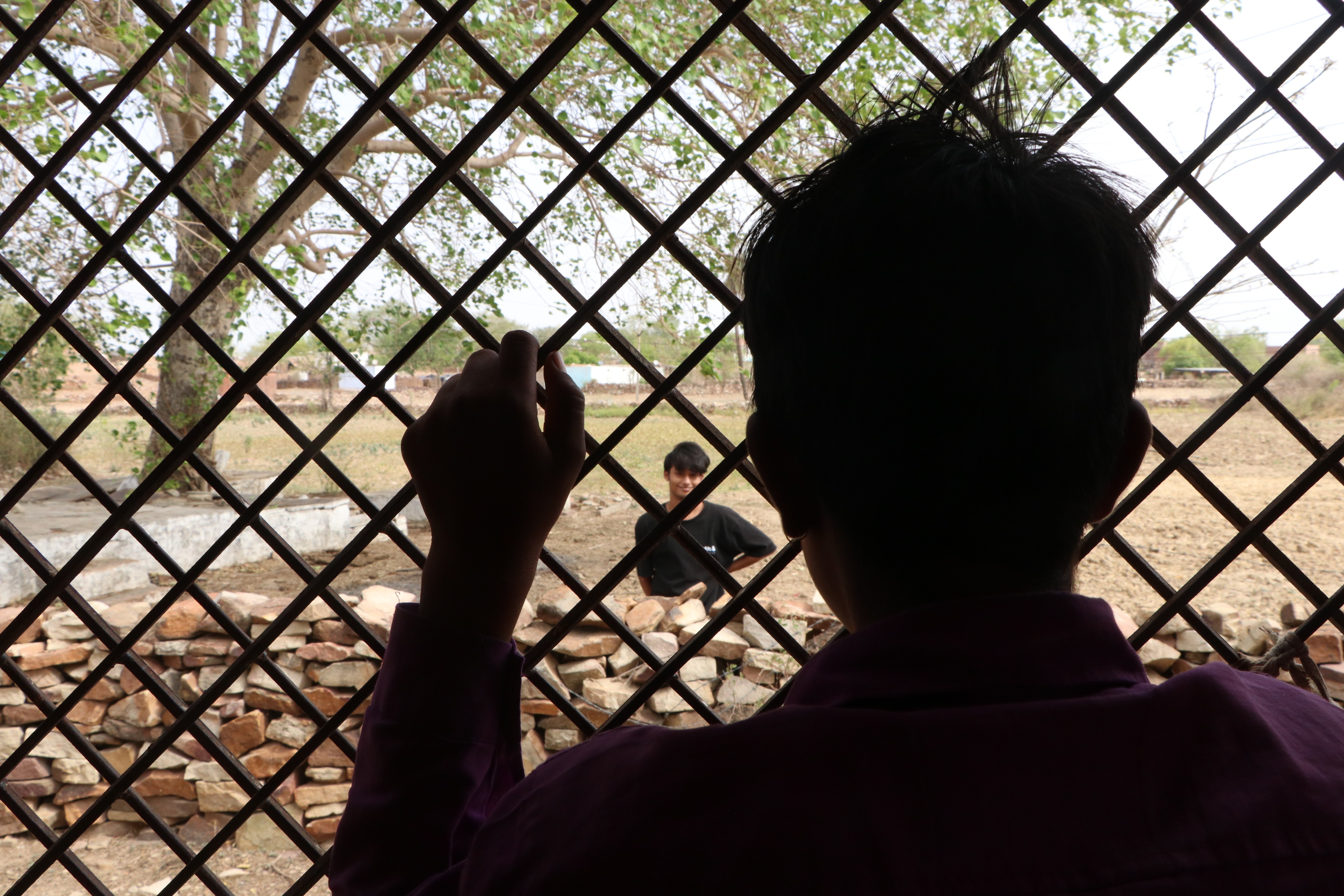A community member looks through a metal lattice.