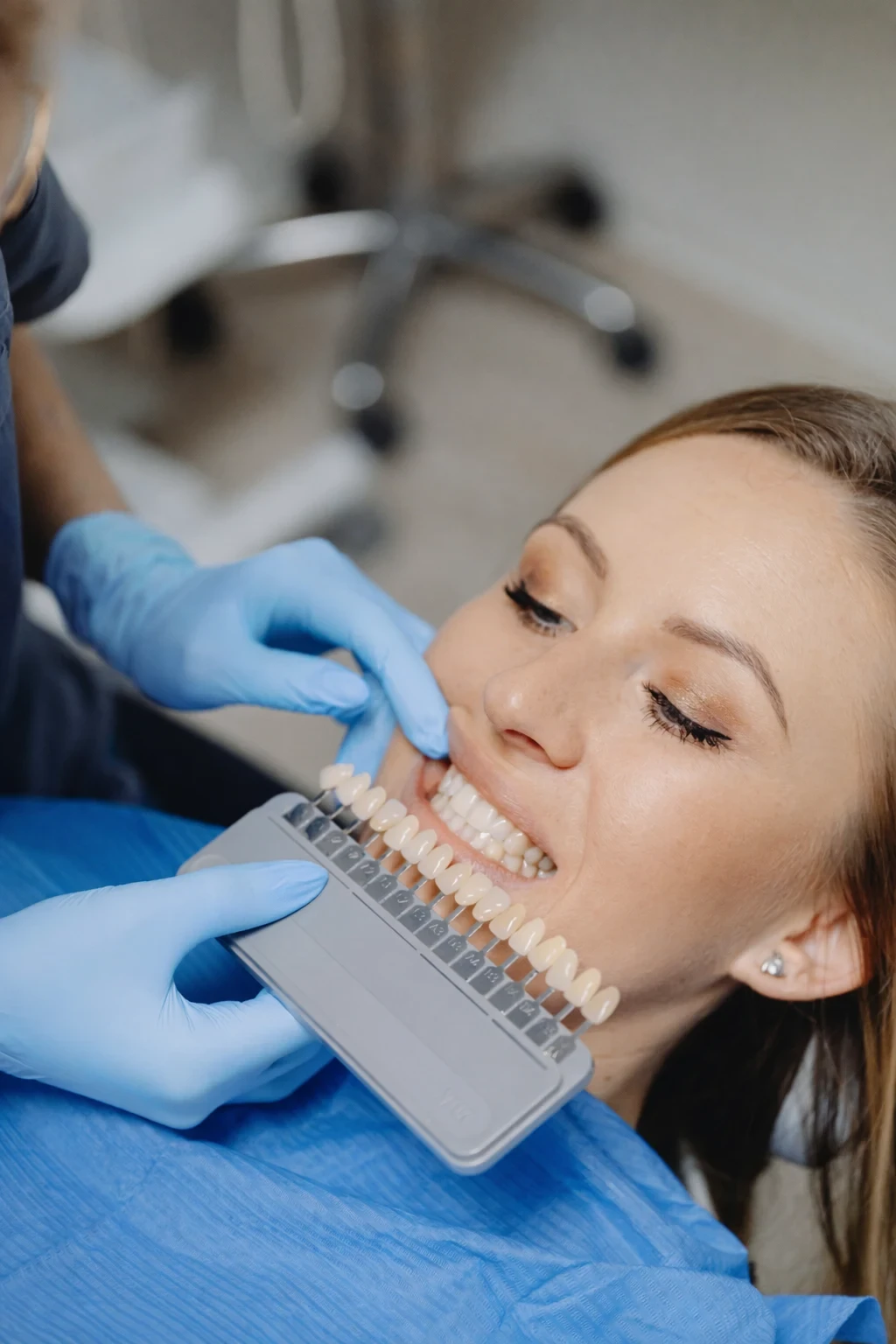 Dentist matching tooth shade using a dental color guide during treatment