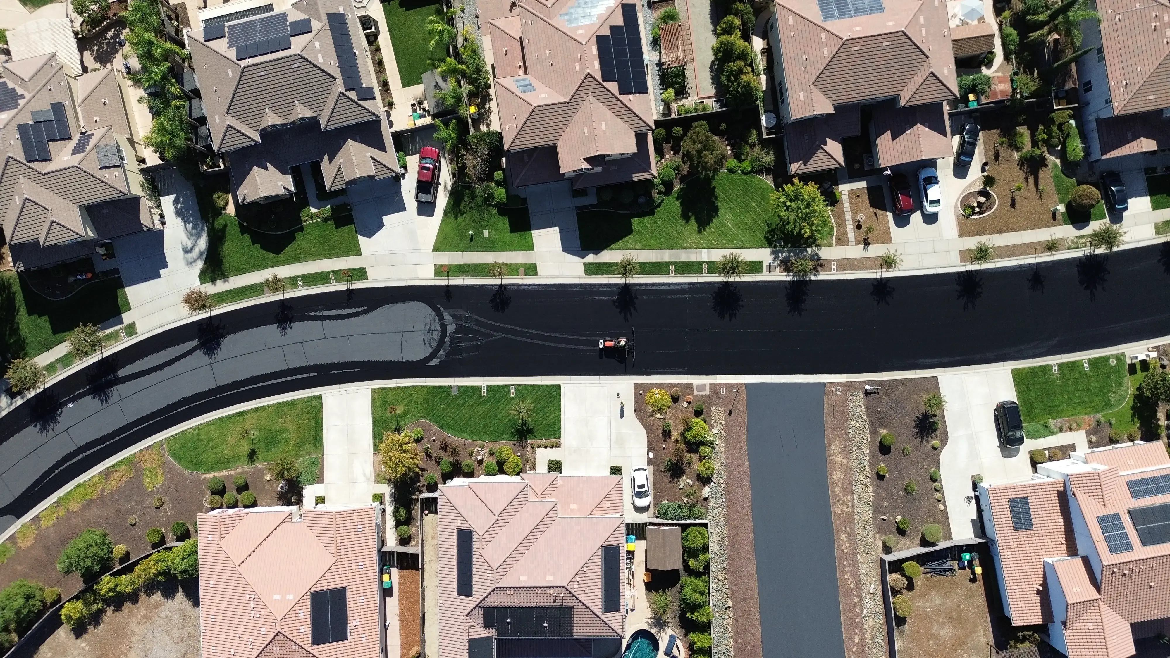 Aerial drone photo of neighborhood street being seal coated