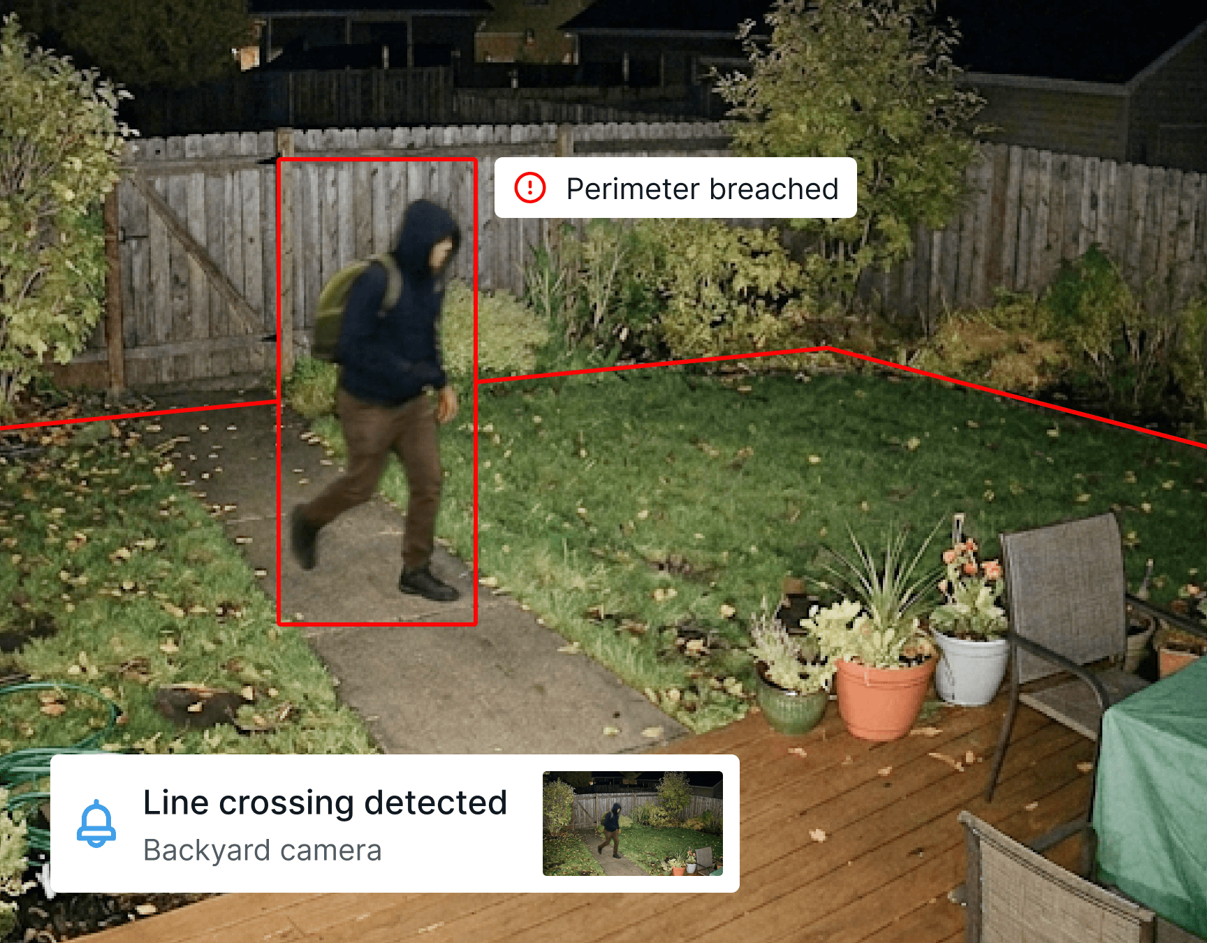 Man in hoodie entering someone's backyard at night and tripping the security system
