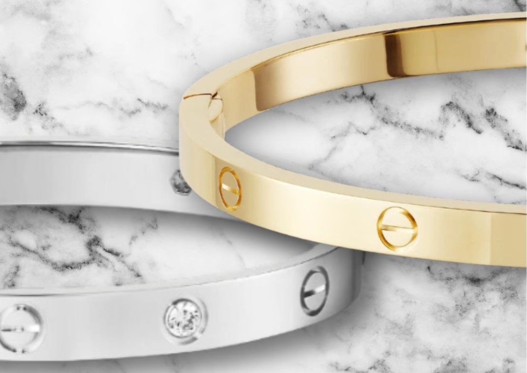 Elegant, stylish, classy, luxurious designer branded Cartier Love bracelets in white gold and gold with diamonds, against a white and black/grey marble table. Design is a symbol of commitment and dedication.