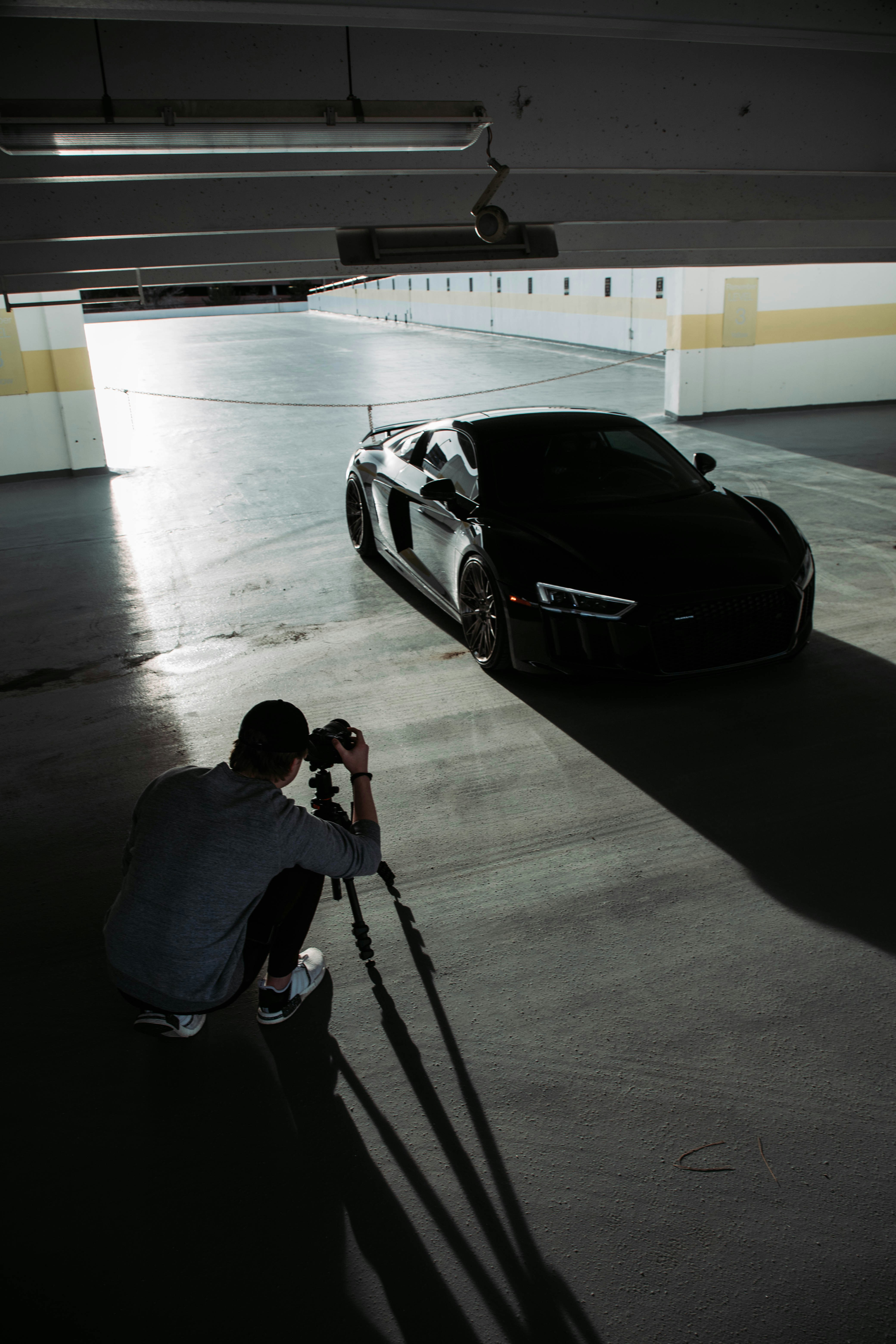 a man taking a picture of a car in a parking garage